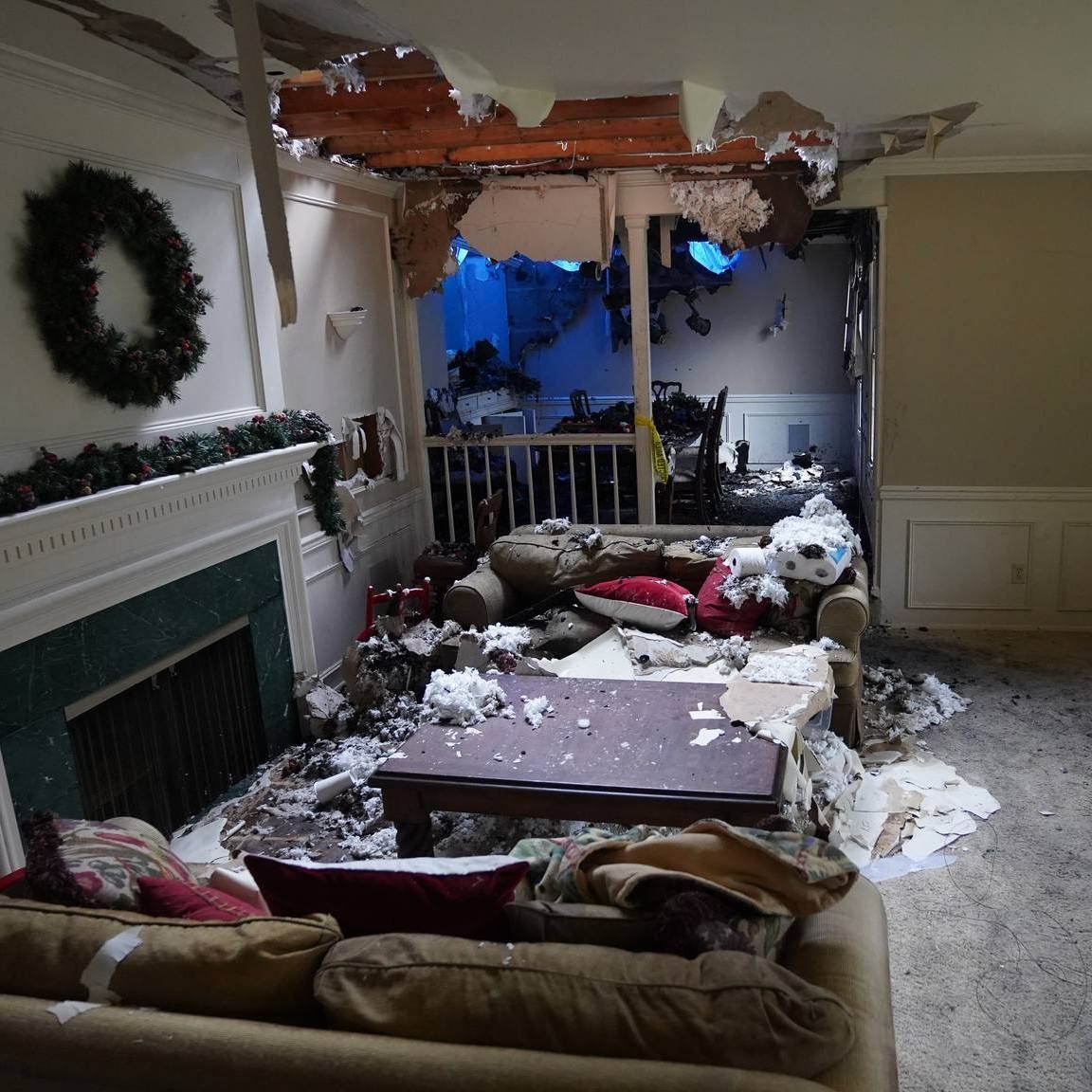 A living room with a couch a fireplace and a wreath on the wall