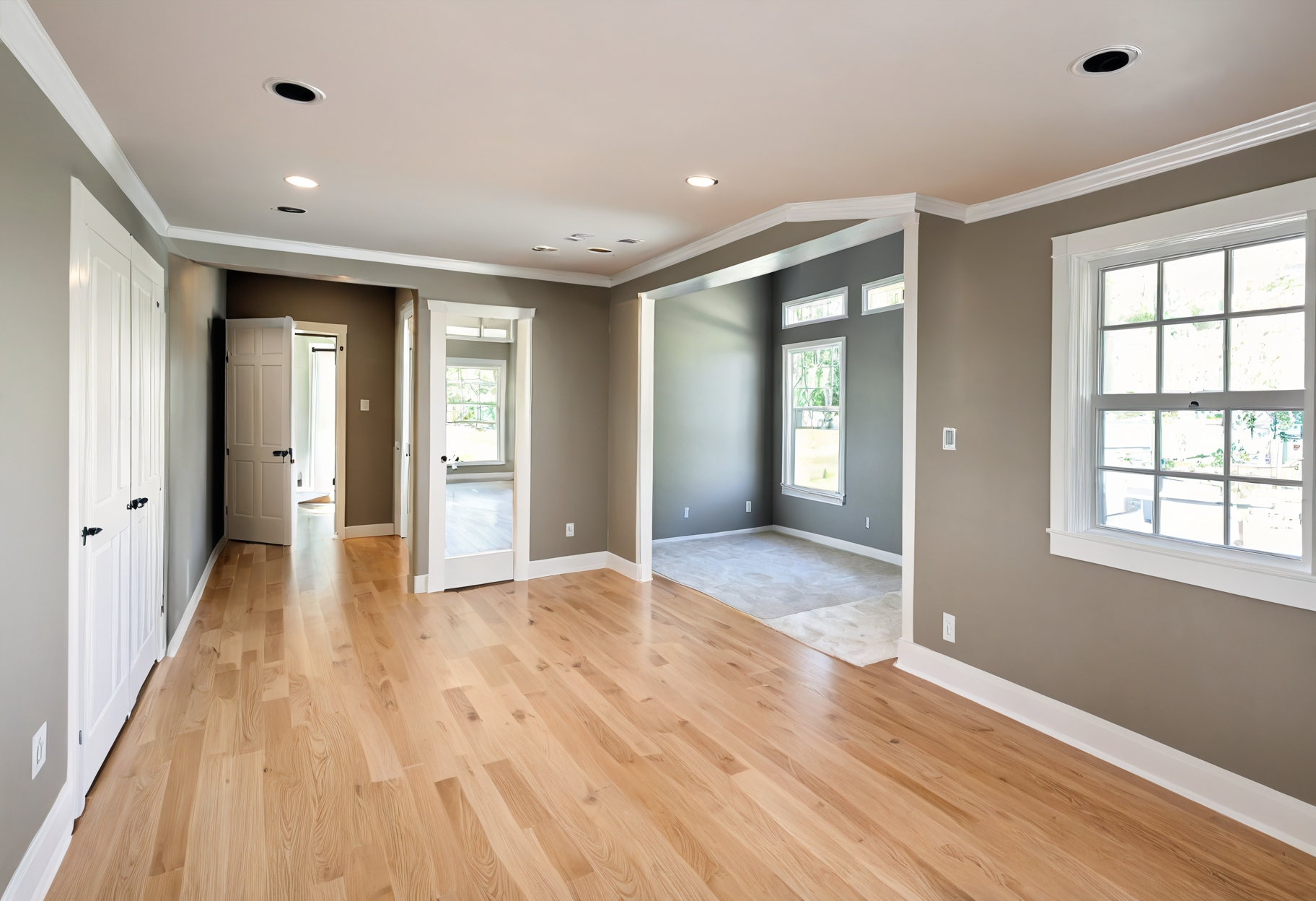 An empty living room with hardwood floors and gray walls
