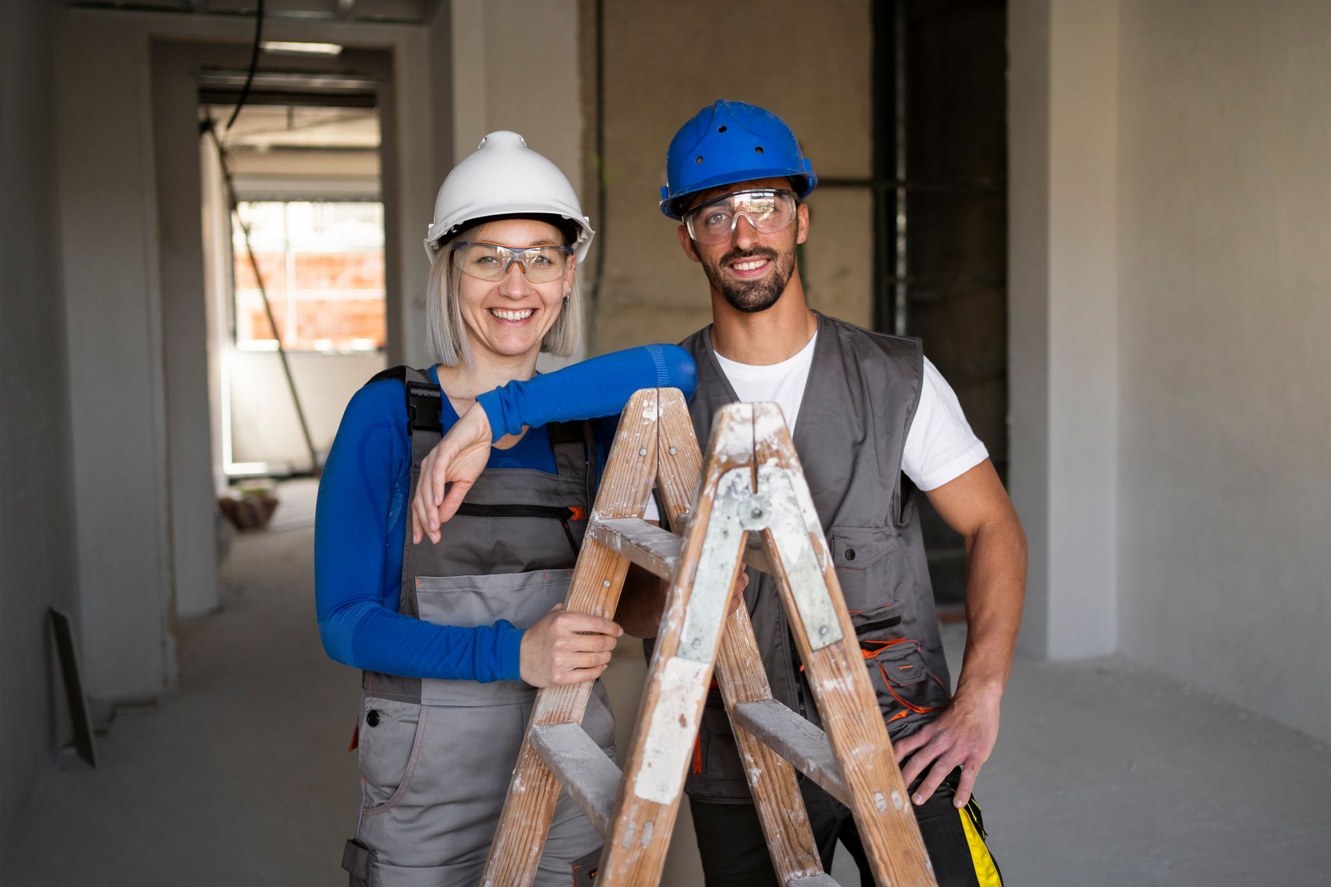 A man and a woman are standing next to each other holding a ladder.