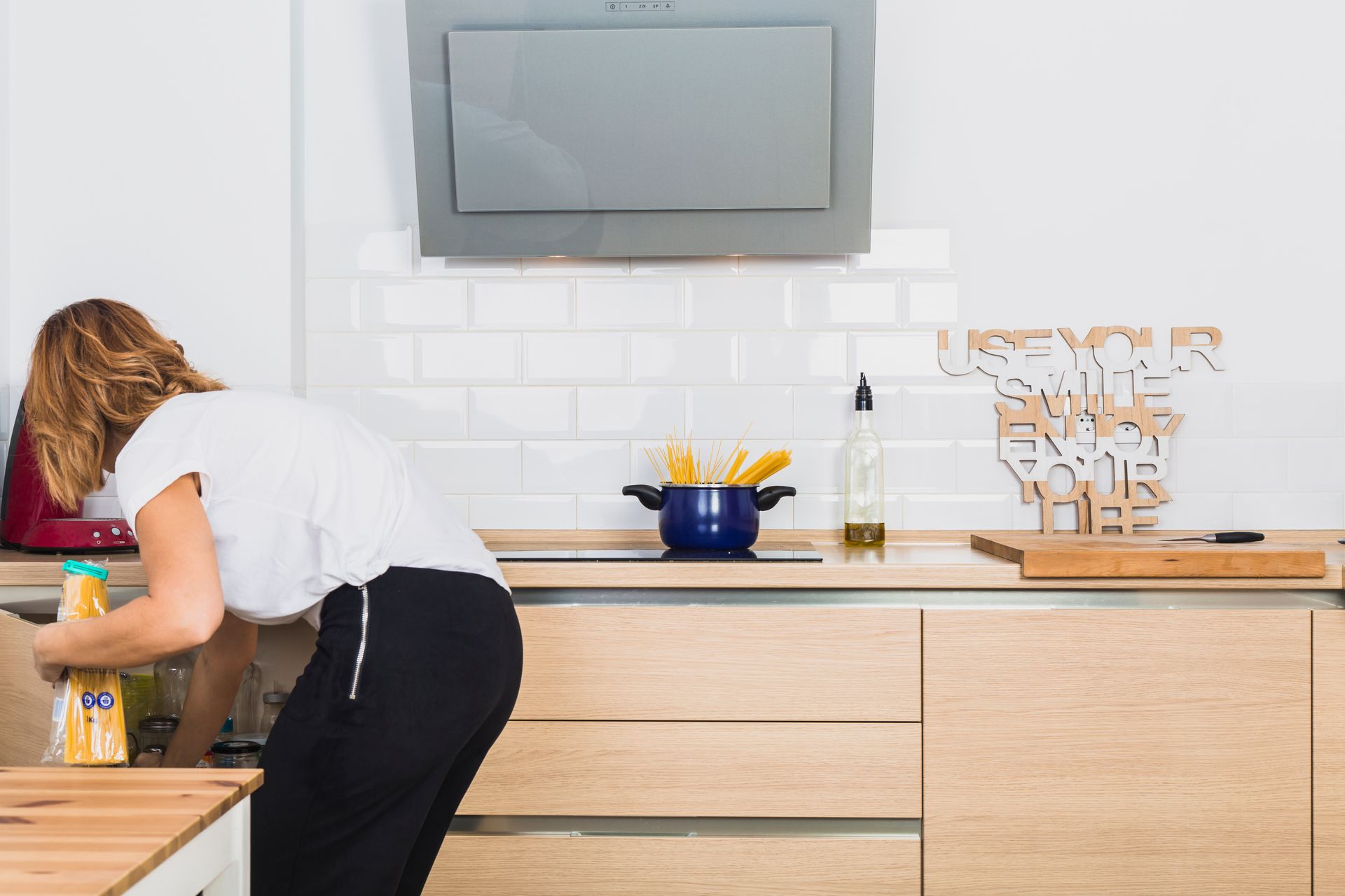 A woman is cleaning a kitchen counter with a spray bottle.