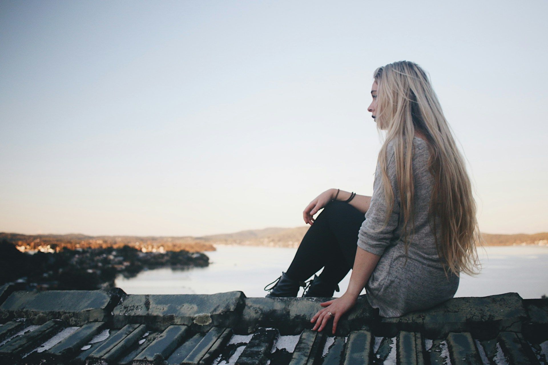 A woman is sitting on a ledge overlooking a body of water.