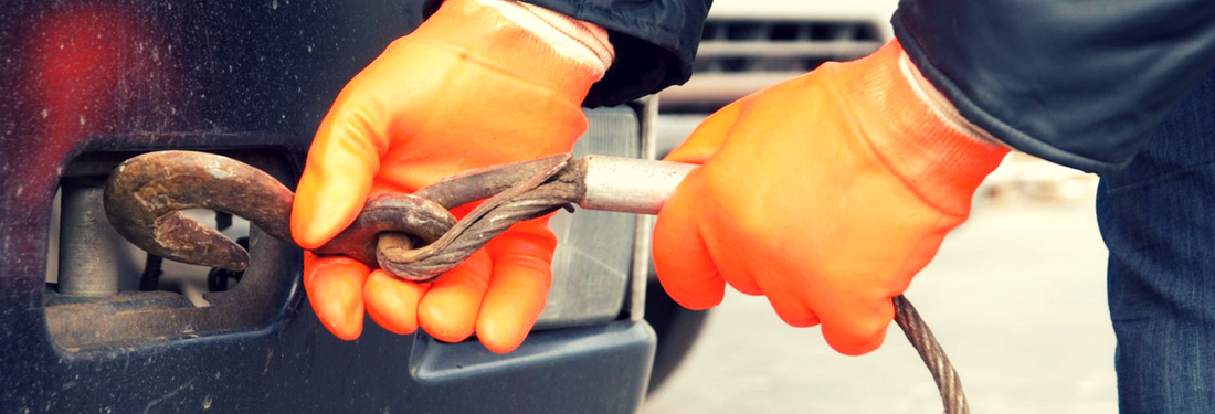 Orange-gloved hands holding a ratchet on a vehicle wheel lug nut