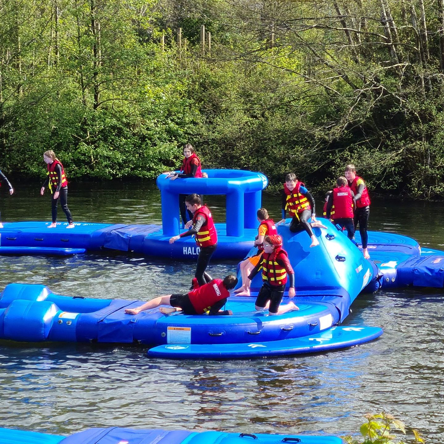 Children wearing life jackets playing on a inflatable aqua park