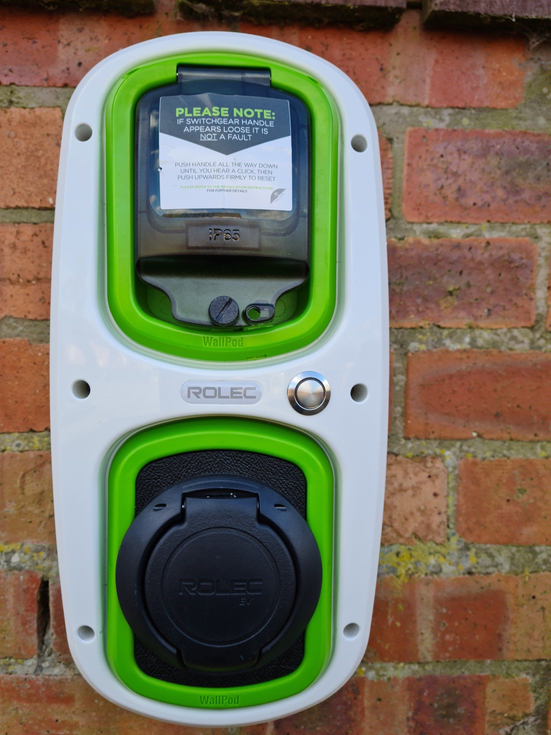 A brick wall with a green and white ev charger