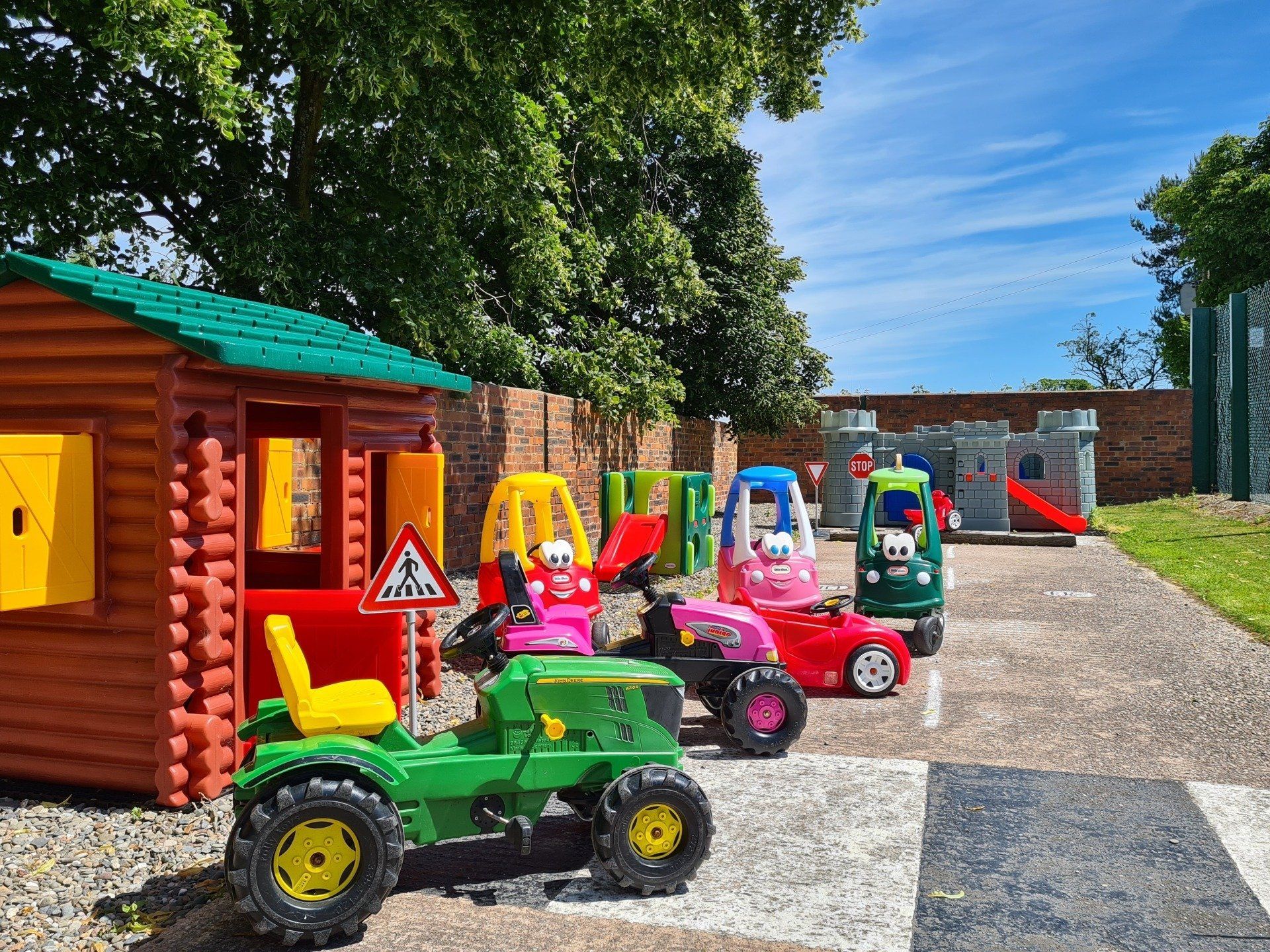 Toddler play area with Bubble cars, Wendy House, Play castle on a sunny day with trees