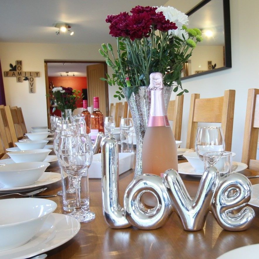 Laid dining table with white crockery , wine glasses and wine bottles