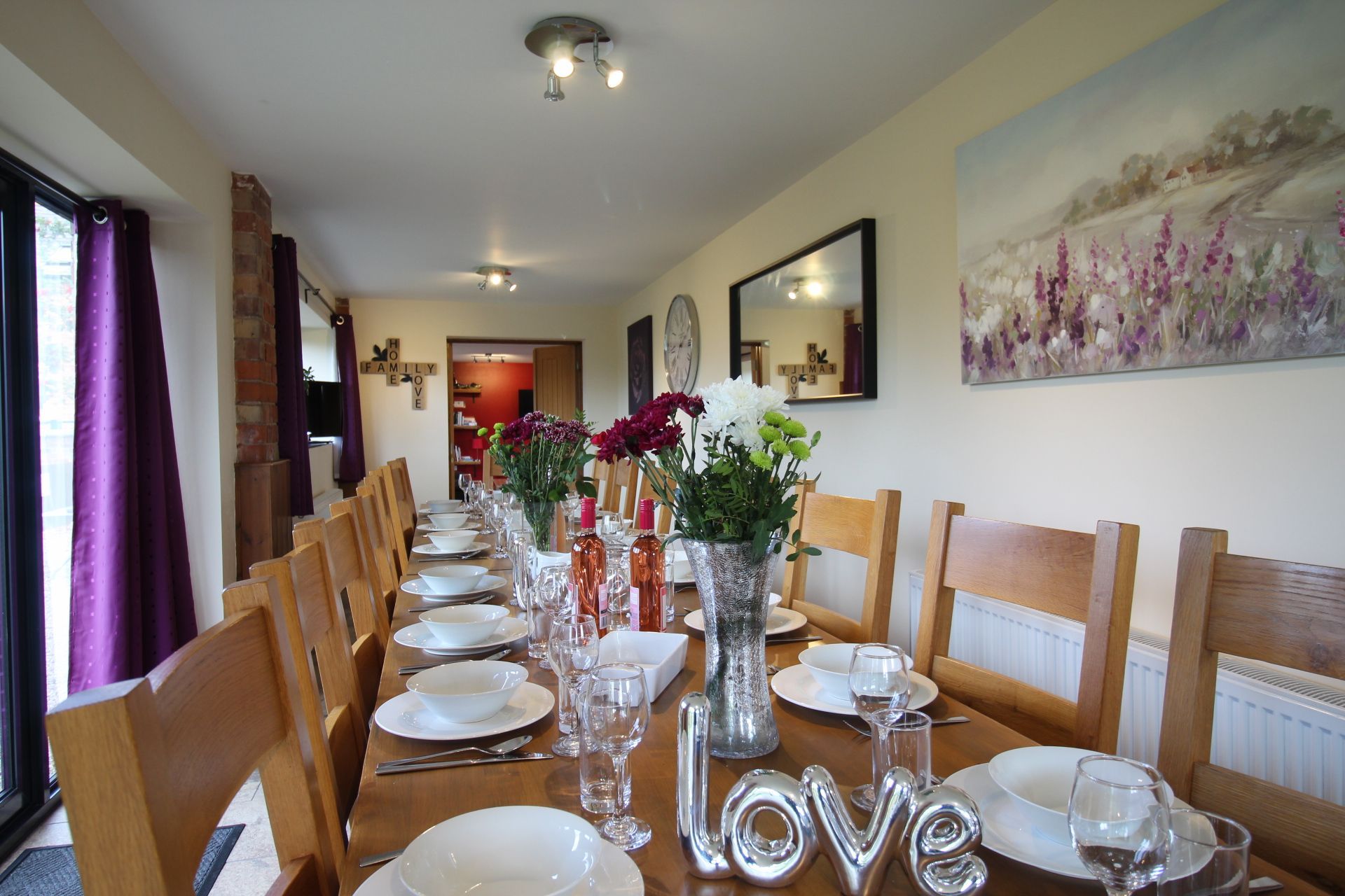Laid dining table with white crockery, wine glasses, flowers and wine