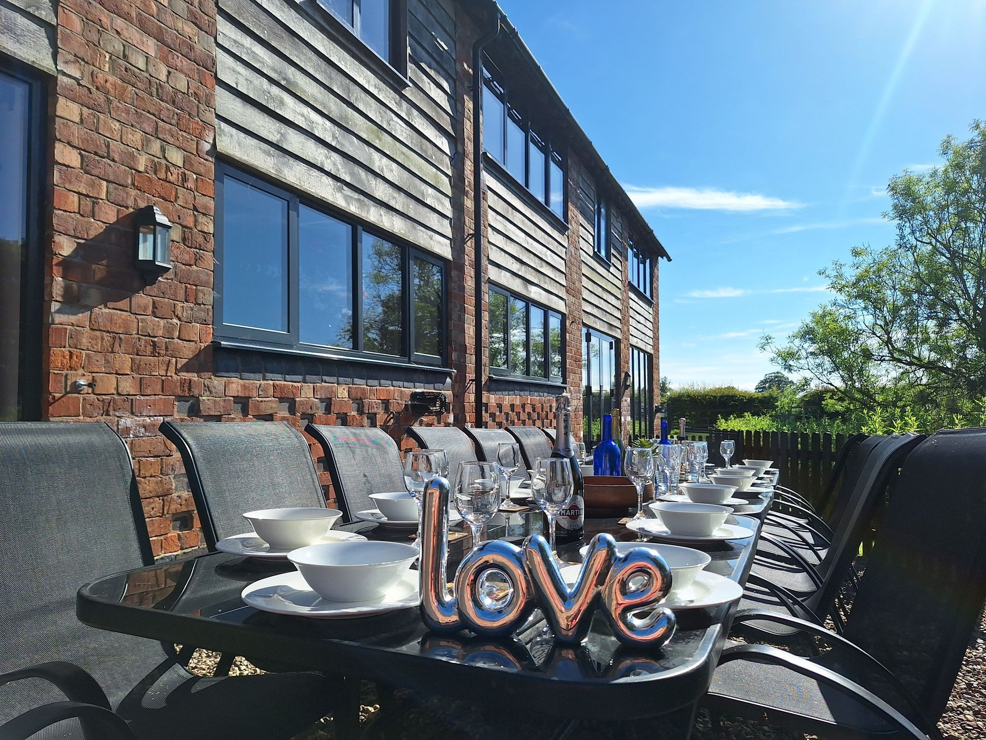 Stone and wooden barn with laid patio table on a sunny day