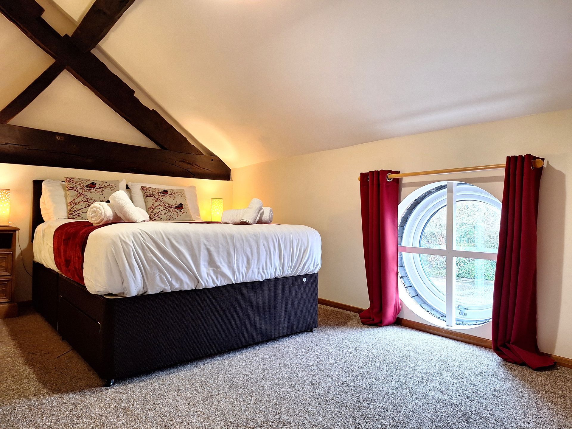 Double bedroom with round window and beams