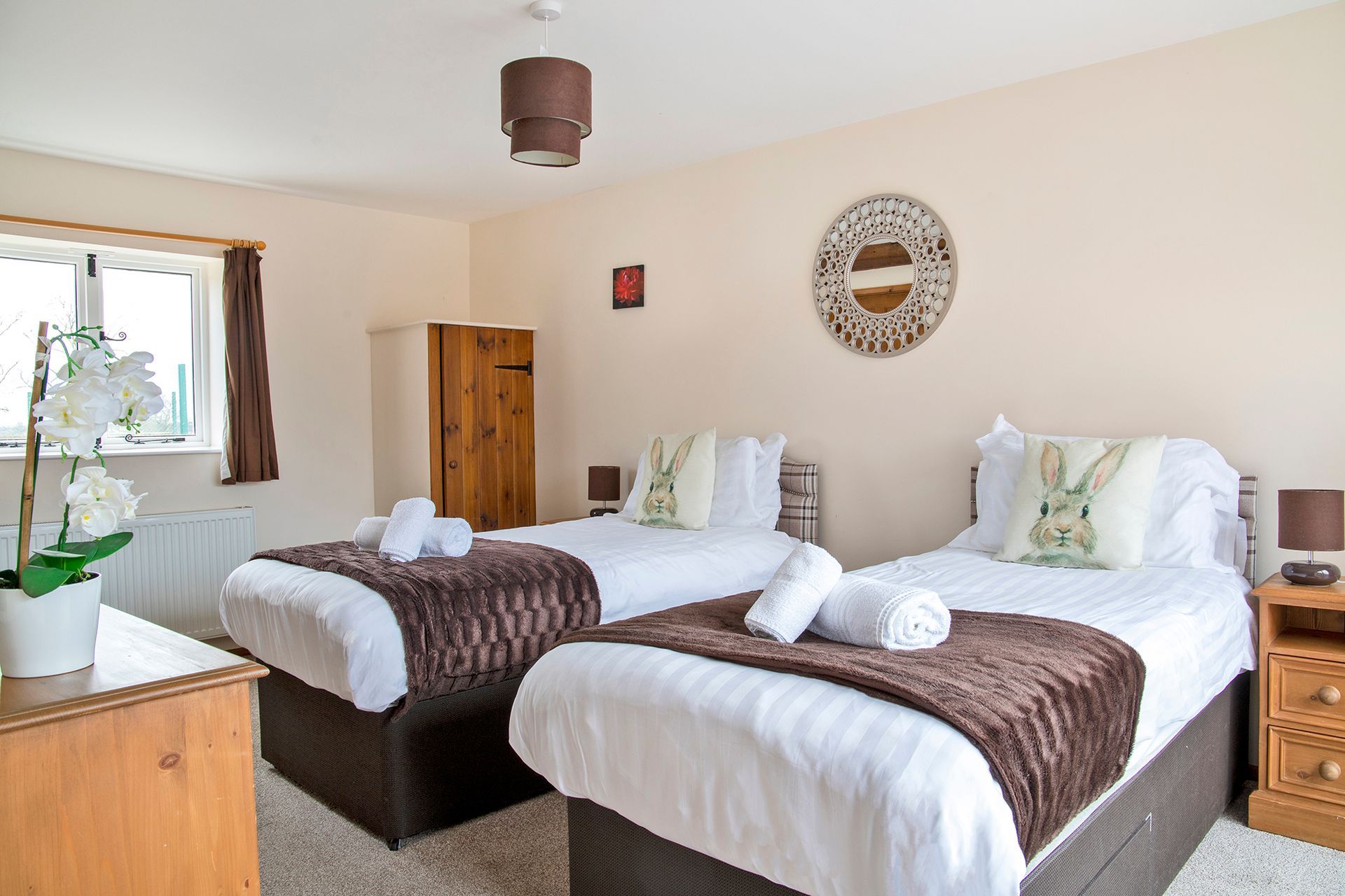 Twin bedroom with white linen, rolled towels and rabbit cushions