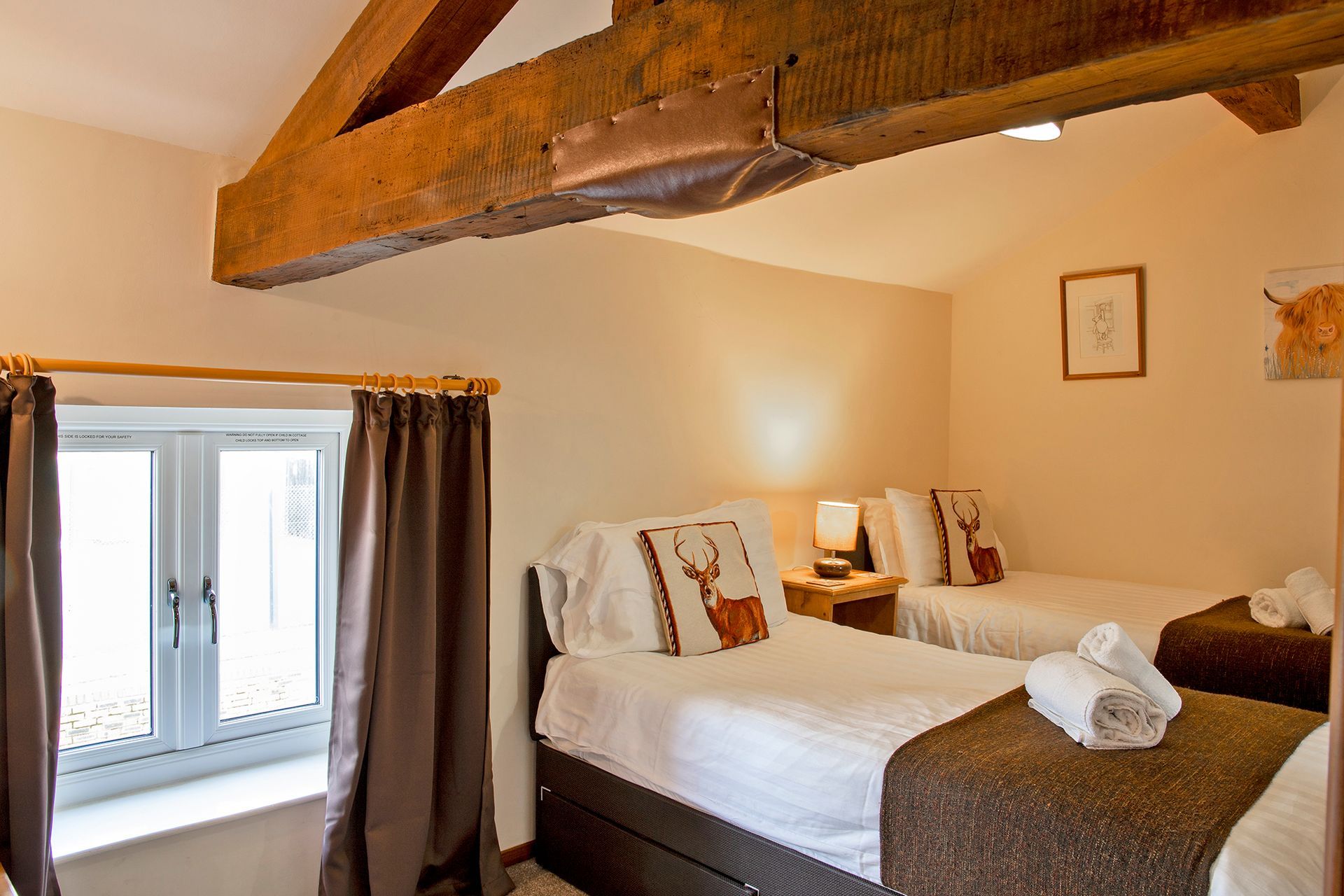 Twin bedroom with large oak beam, window and stag cushions