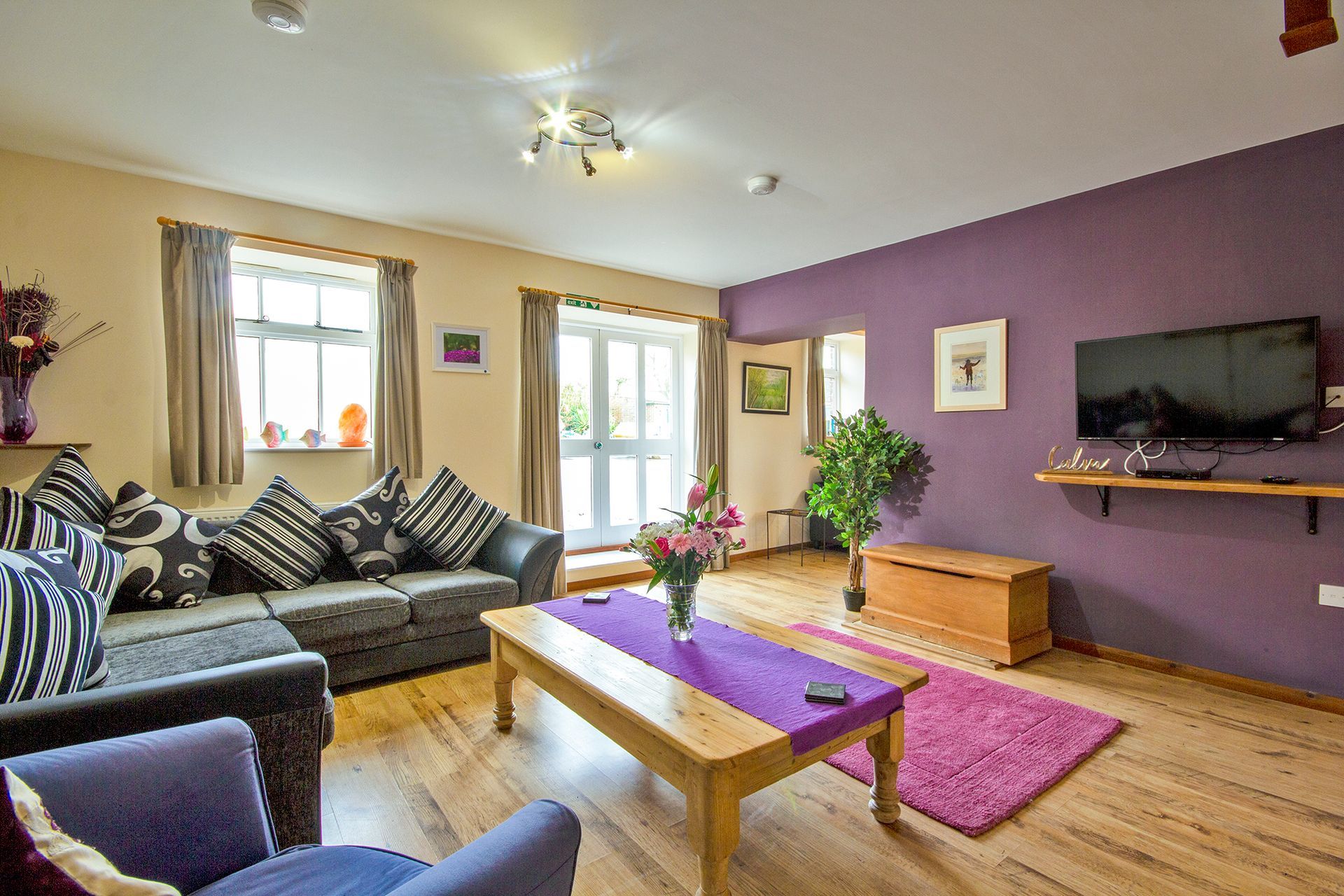 Sitting room with sofa and flowers and large patio doors in a cottage