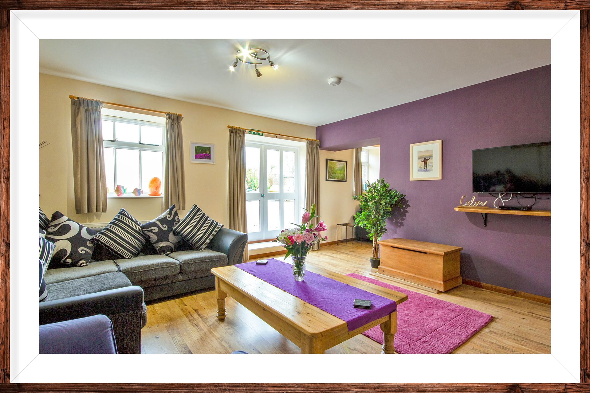 Sitting room with sofa and purple walls in Emma's Dairy holiday let
