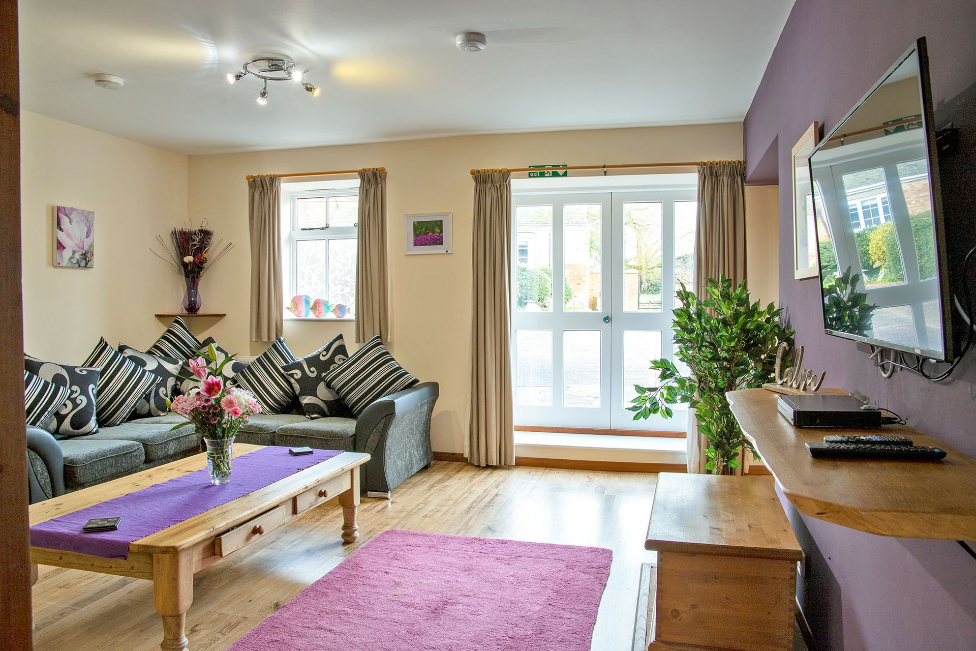 Sitting room with large patio doors Tv and vase of flowers