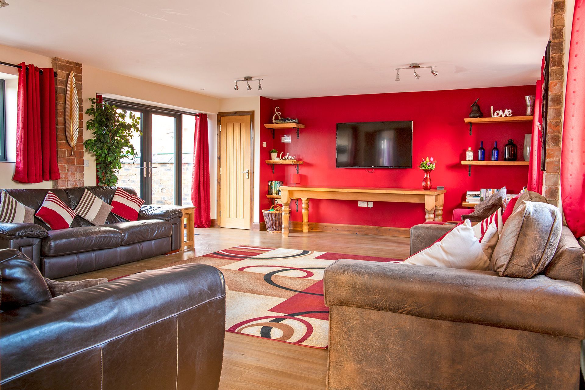 Spacious sitting room with sofa's and patio doors and Tv and a red wall
