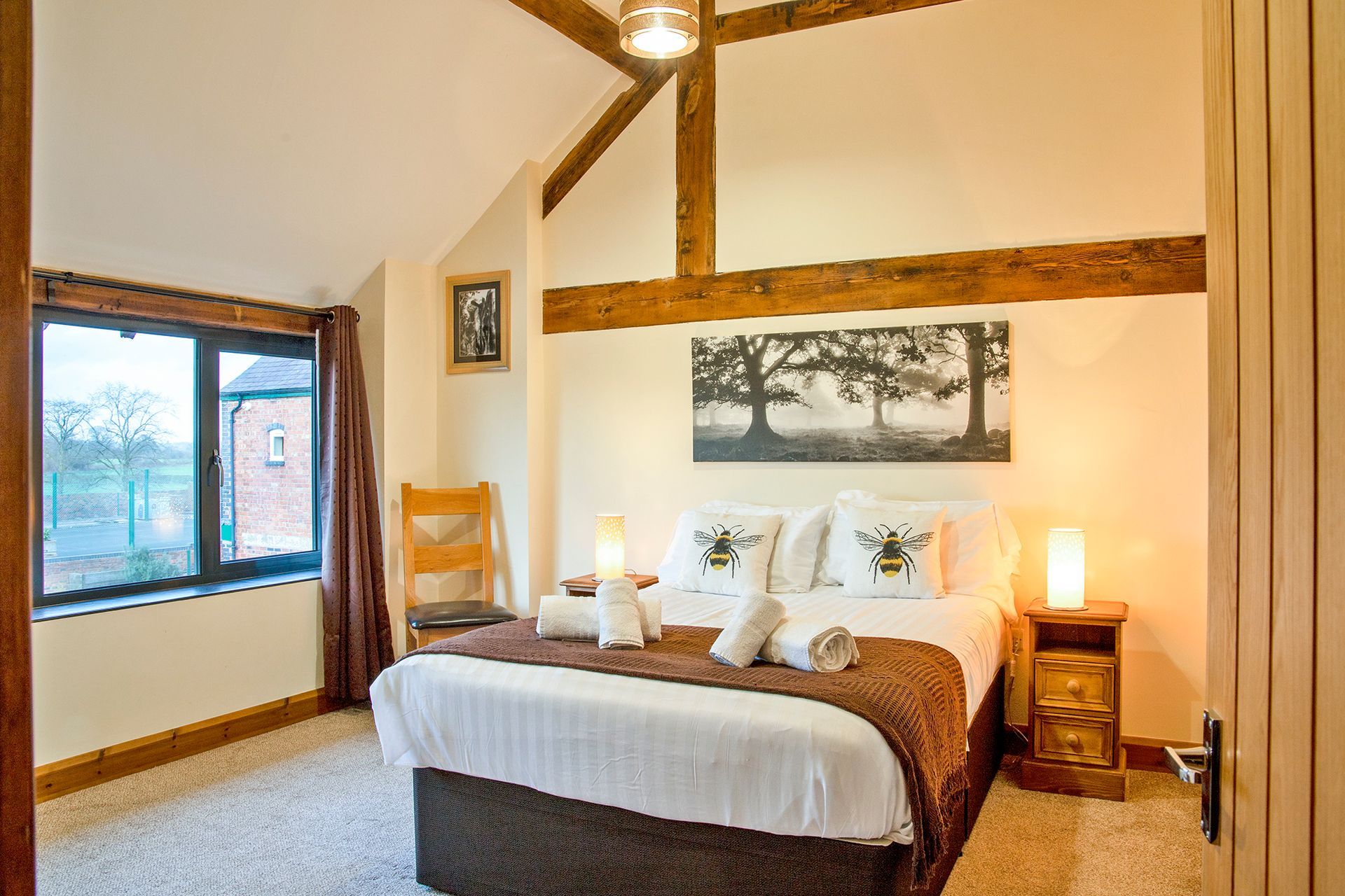 Double bedroom with rolled towels and bumblebee cushions and large window