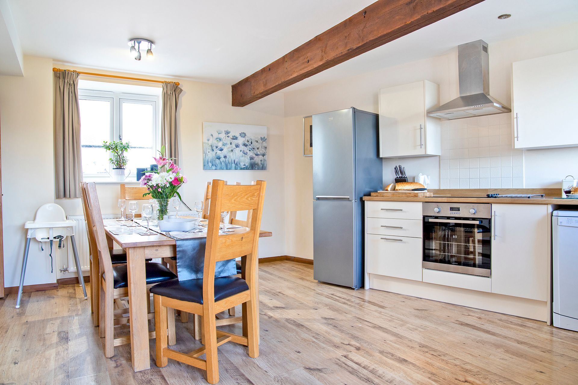 Laid dining table with flowers in an open plan kitchen with fridge and oven