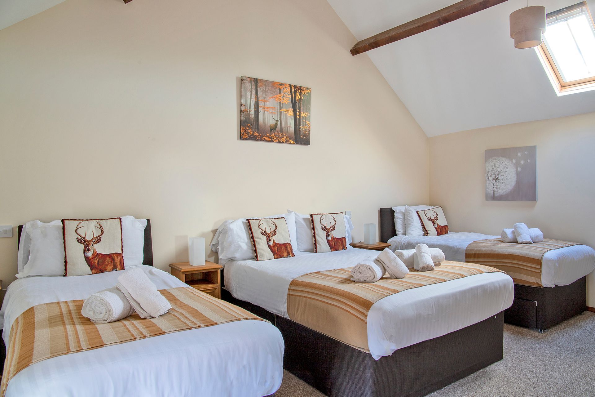 Bedroom with 3 beds, white linen and cushions with stags on