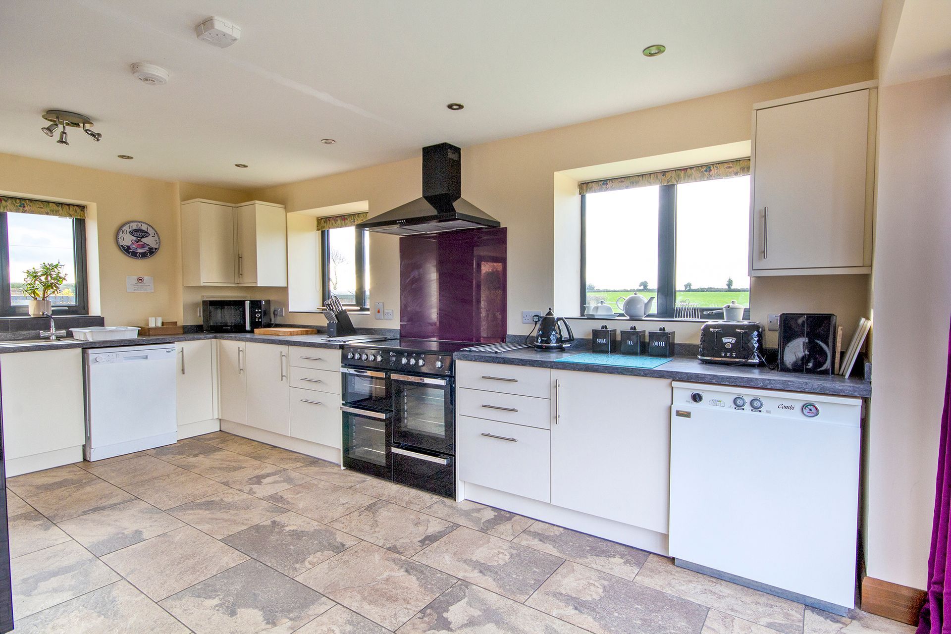 Modern cream kitchen with range oven, purple splash back and extractor fan
