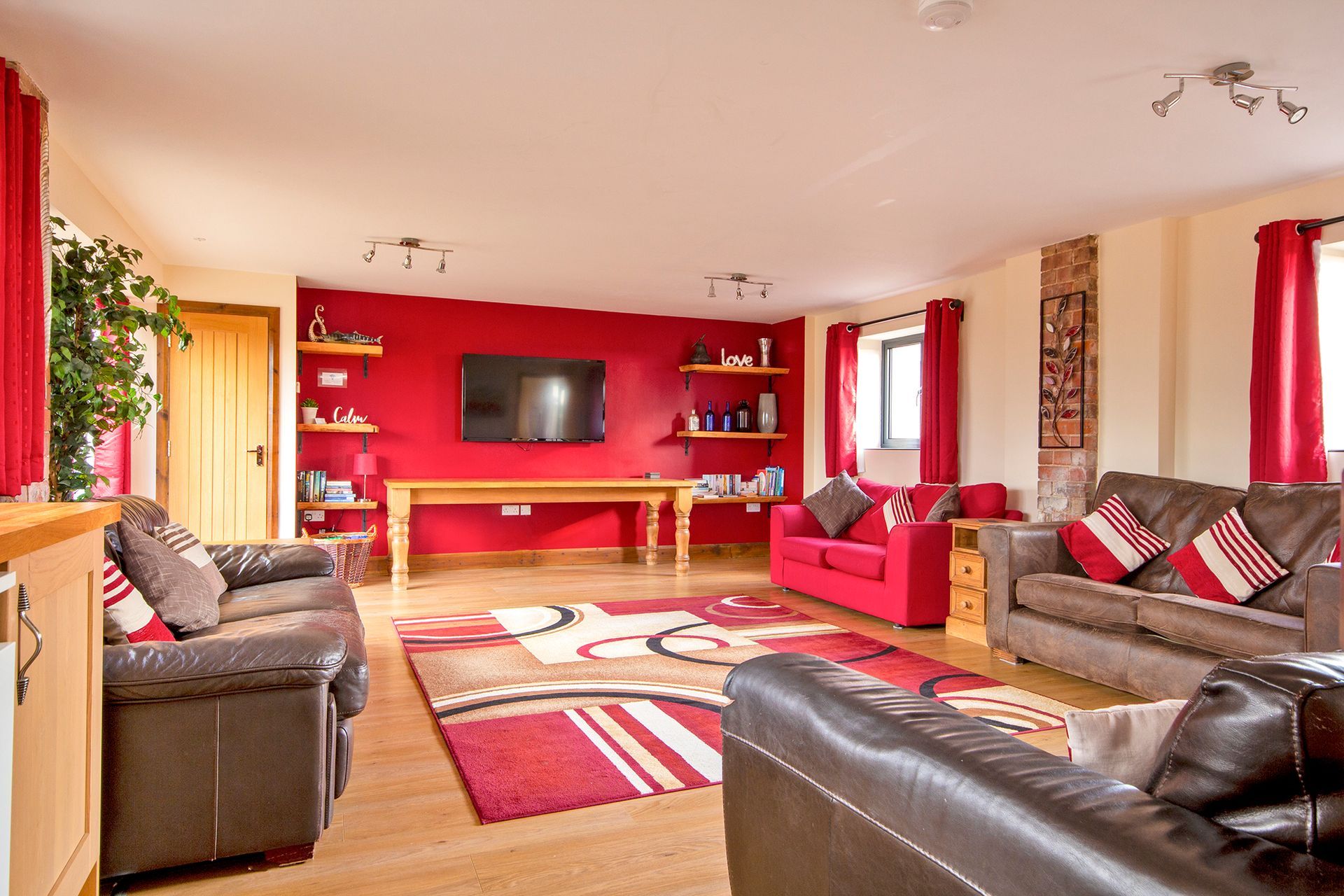 Large sitting room with red wall, sofas and TV
