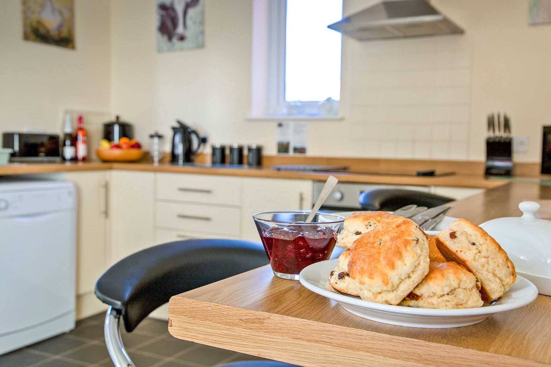 A plate of scones and dish of jam on a kitchen side