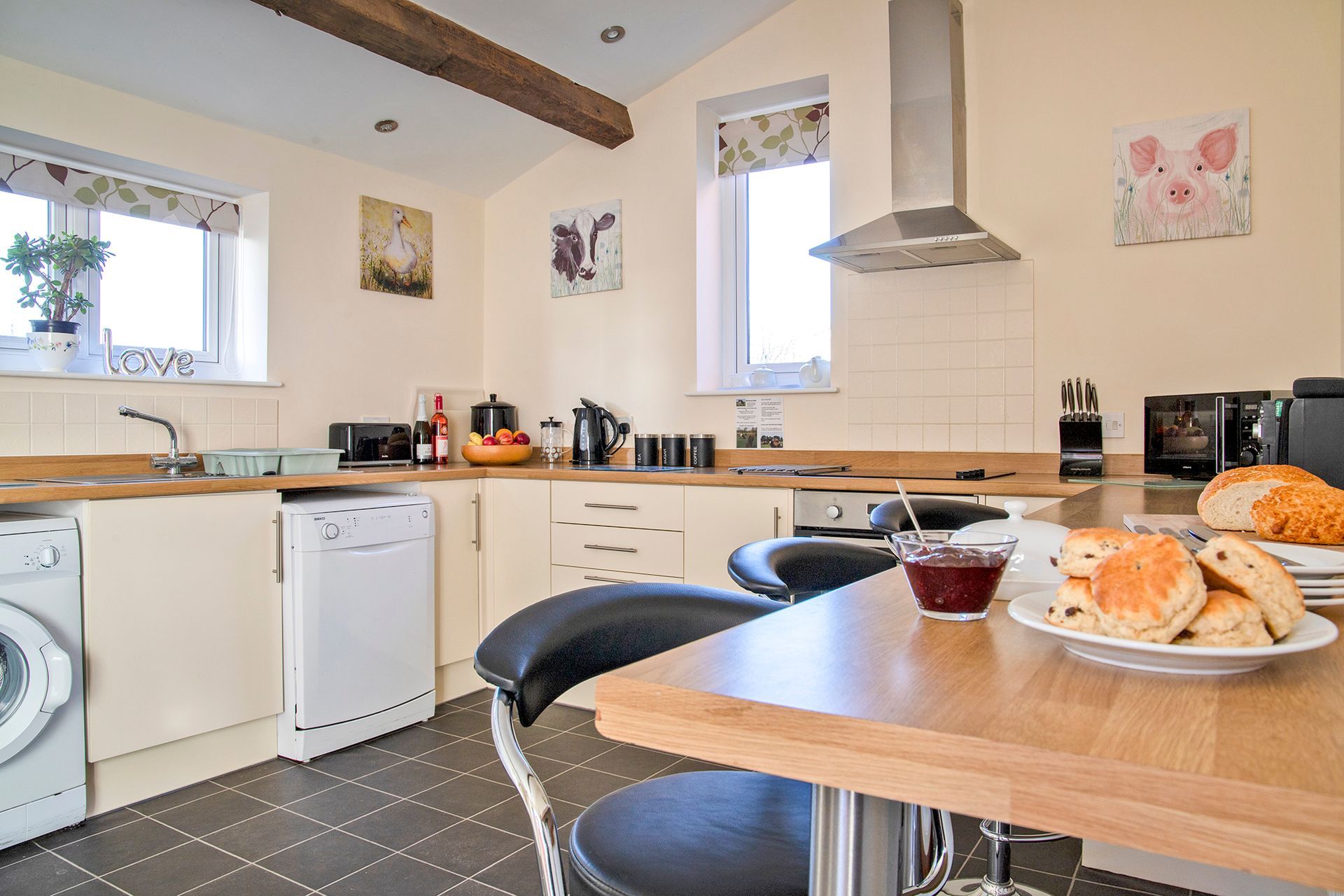 A plate of scones with a dish of jam on a kitchen side with modern cream kitchen in the background