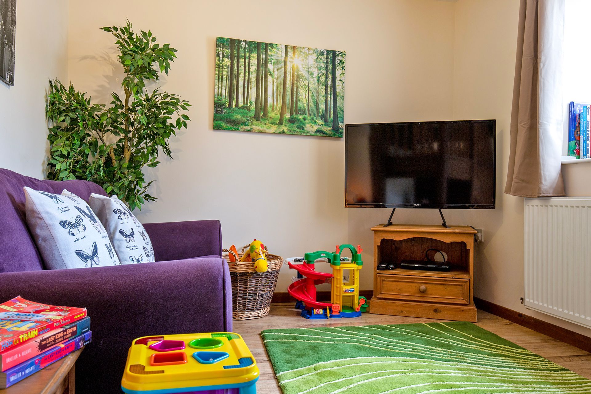 Snug area with purple sofa, TV and toys