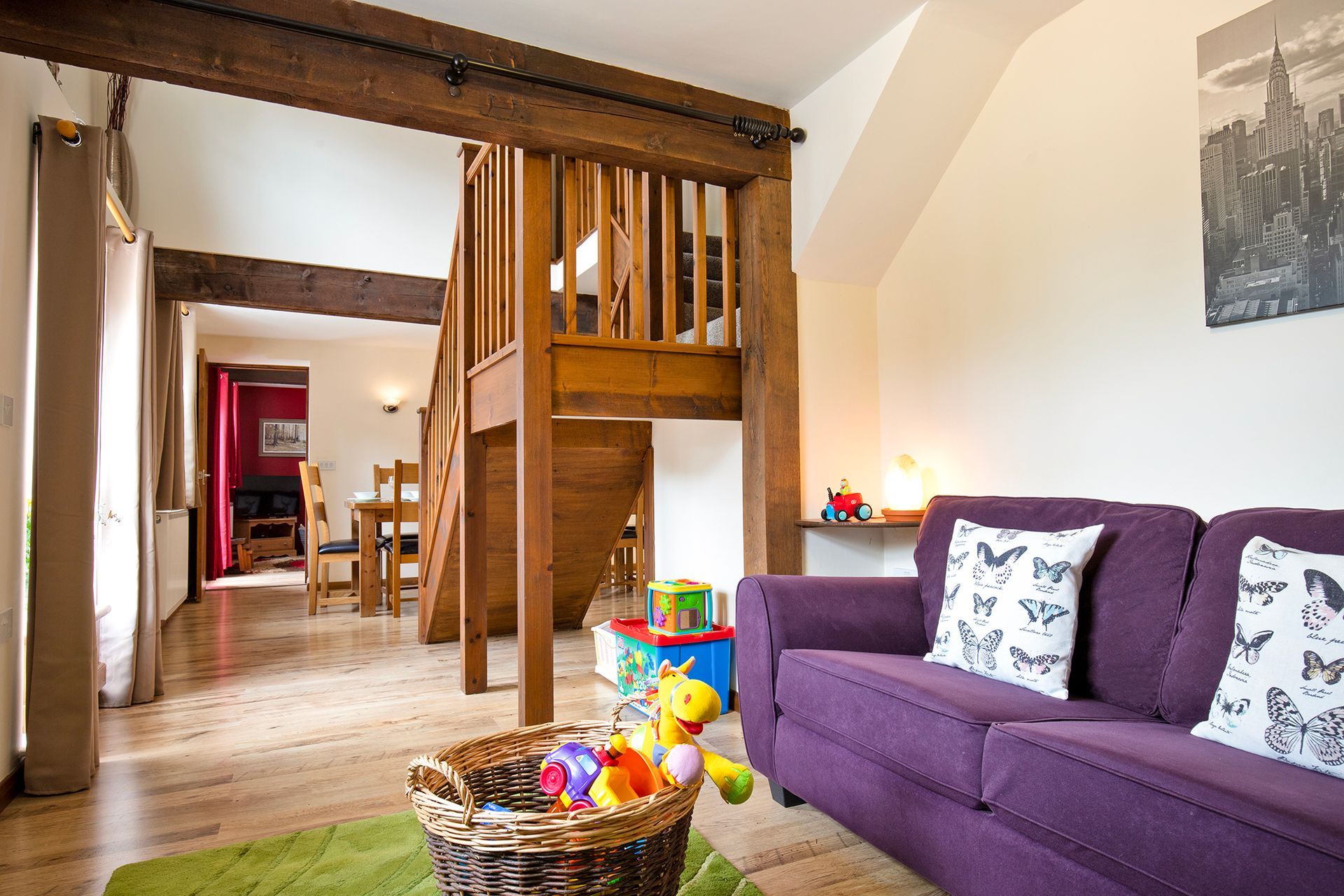 Wooden staircase with beams and a purple sofa in a holiday cottage