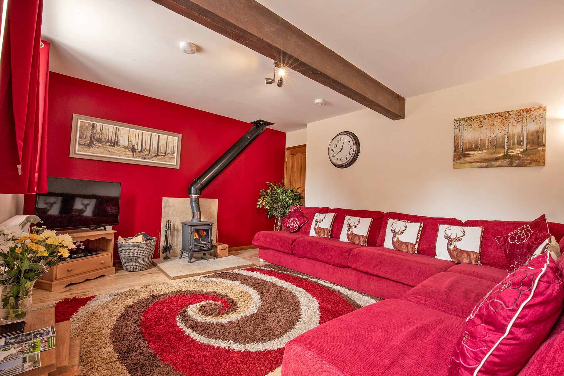 Sitting room with red sofas and cushions with stags on. Wood