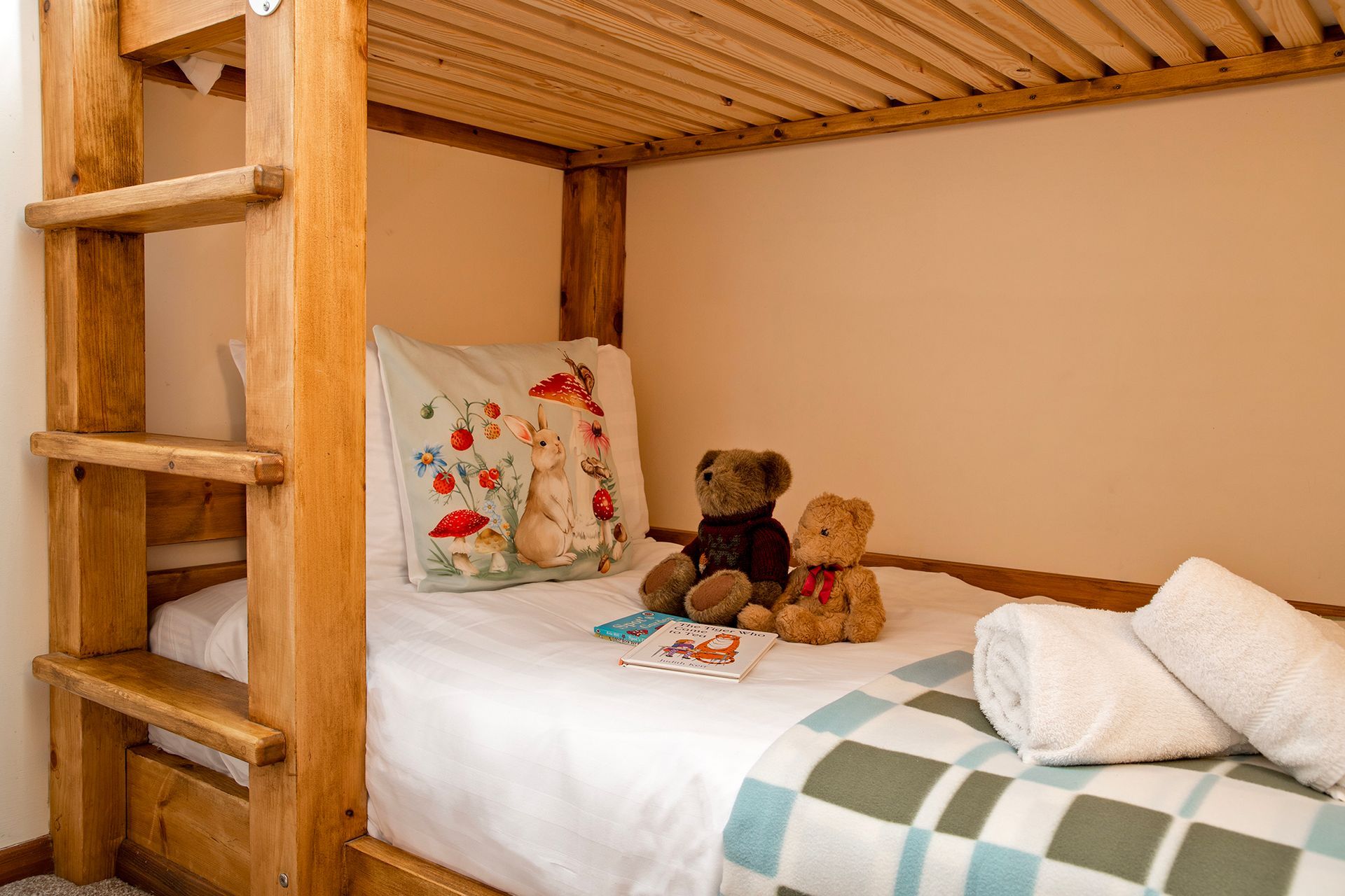 Two teddy bears sitting on children's wooden bunkbeds