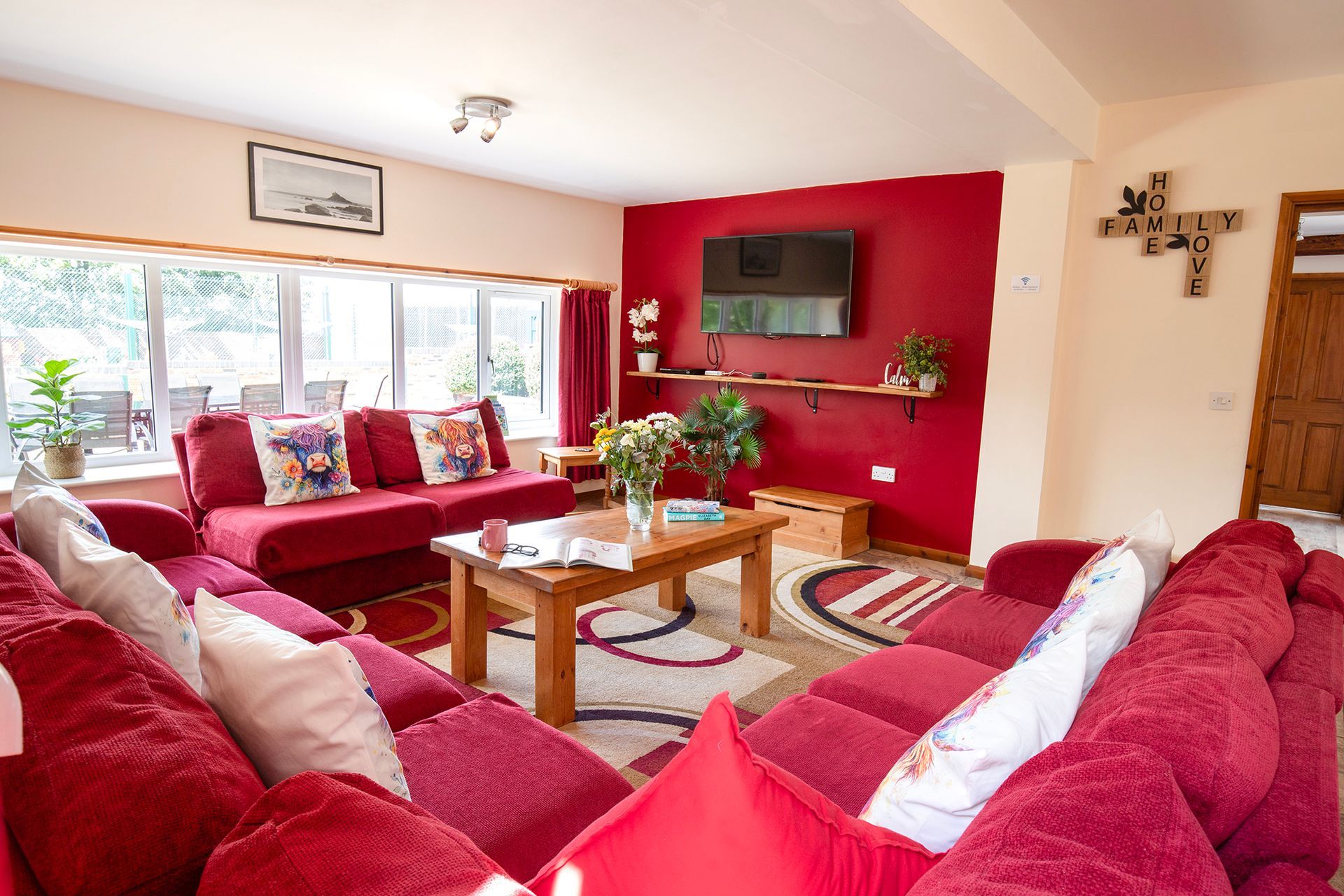 Sitting area with red sofas and red wall with TV and large window