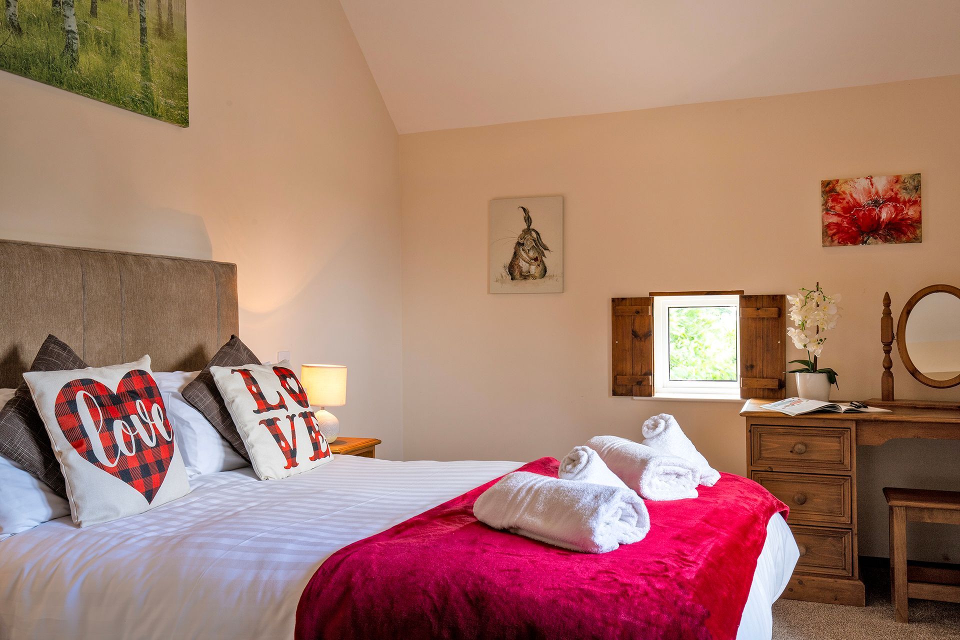 Bedroom with Love cushions, wooden dressing table with mirror and small window