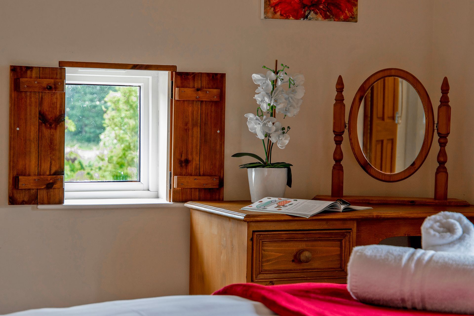 Wooden dressing table with round mirror and small window with countryside views 