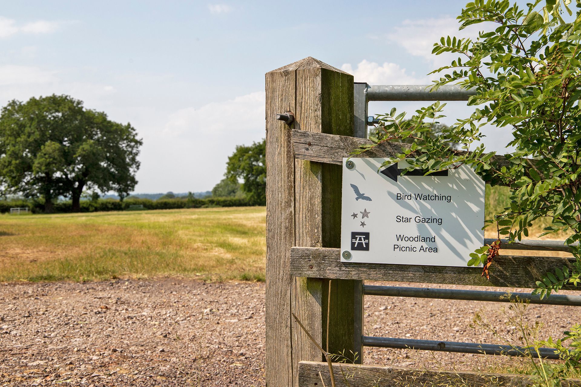 Gates post with a sign and a field behind 
