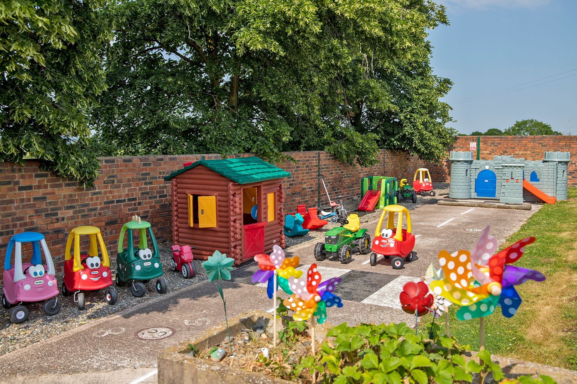 children's play area with plastic ride on toys, Wendy house and grey plastic castle