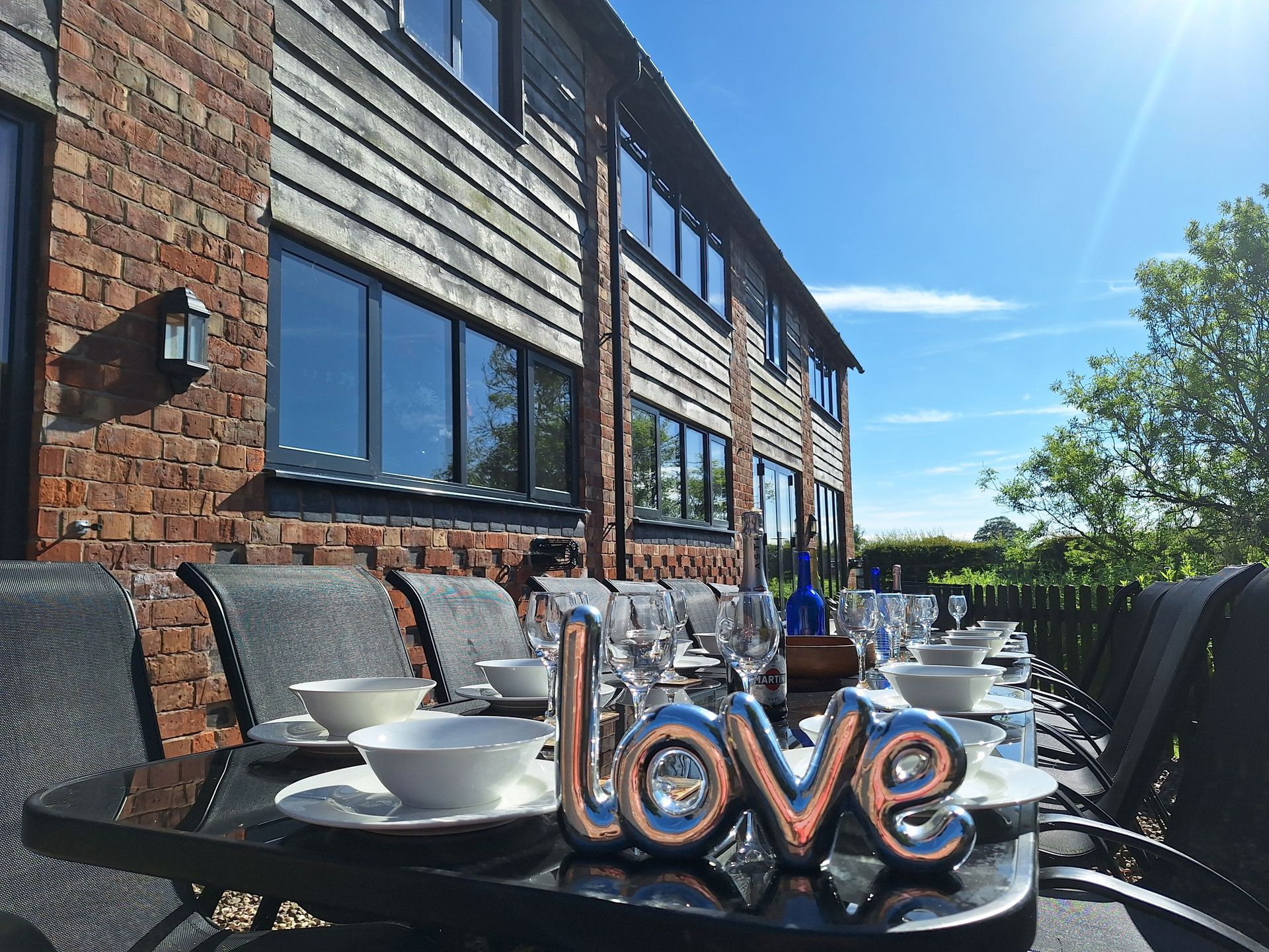 Patio table laid with glasses and crockery in the sunshine