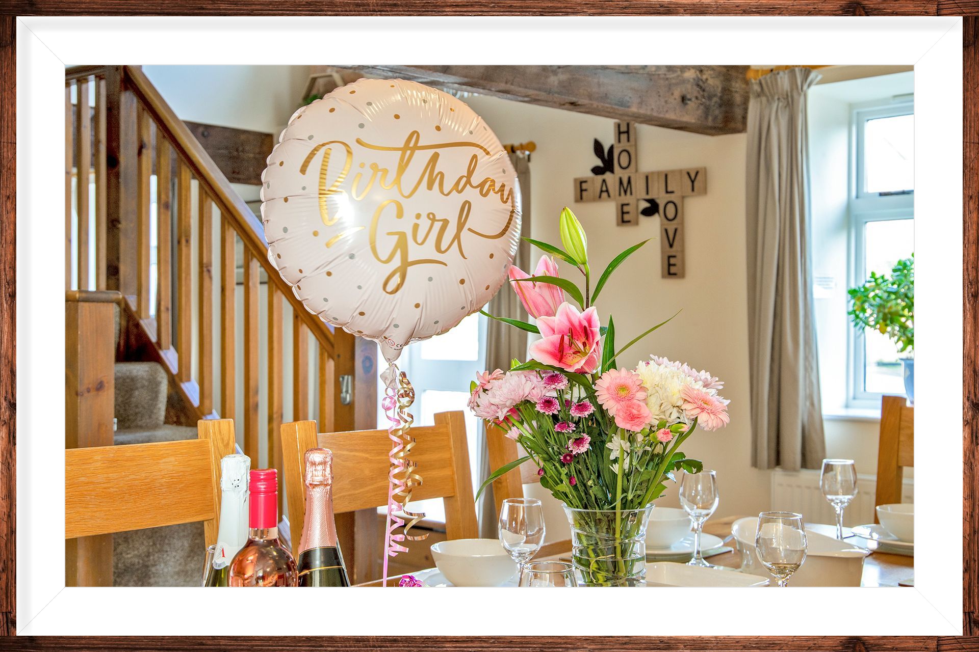 A birthday celebration laid dining table with balloon and flowers in a holiday cottage