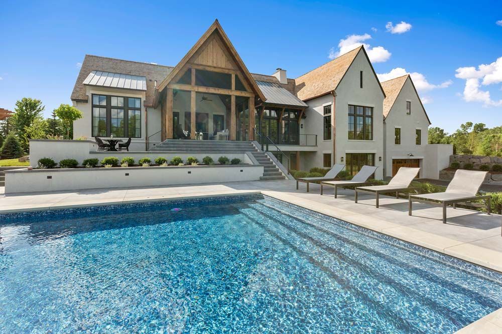 Luxury modern house with a pool, lounge chairs, and a bright blue sky