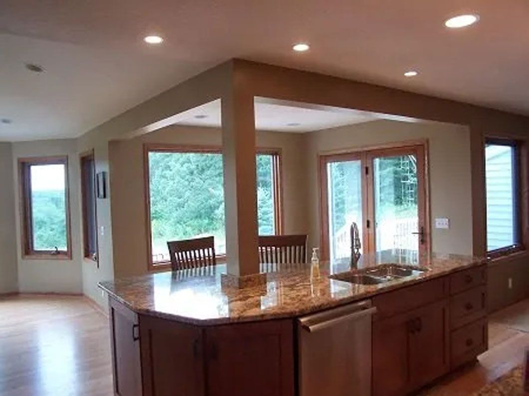 Kitchen with granite countertops, wooden cabinets, and large windows overlooking greenery.