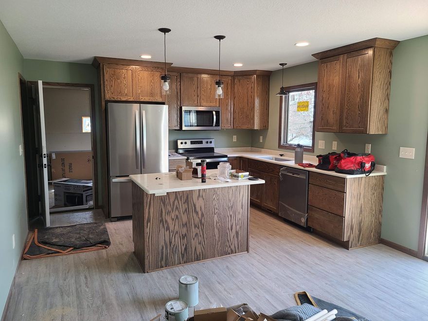 Modern kitchen with wood cabinets, stainless appliances, island, and an open floor plan.