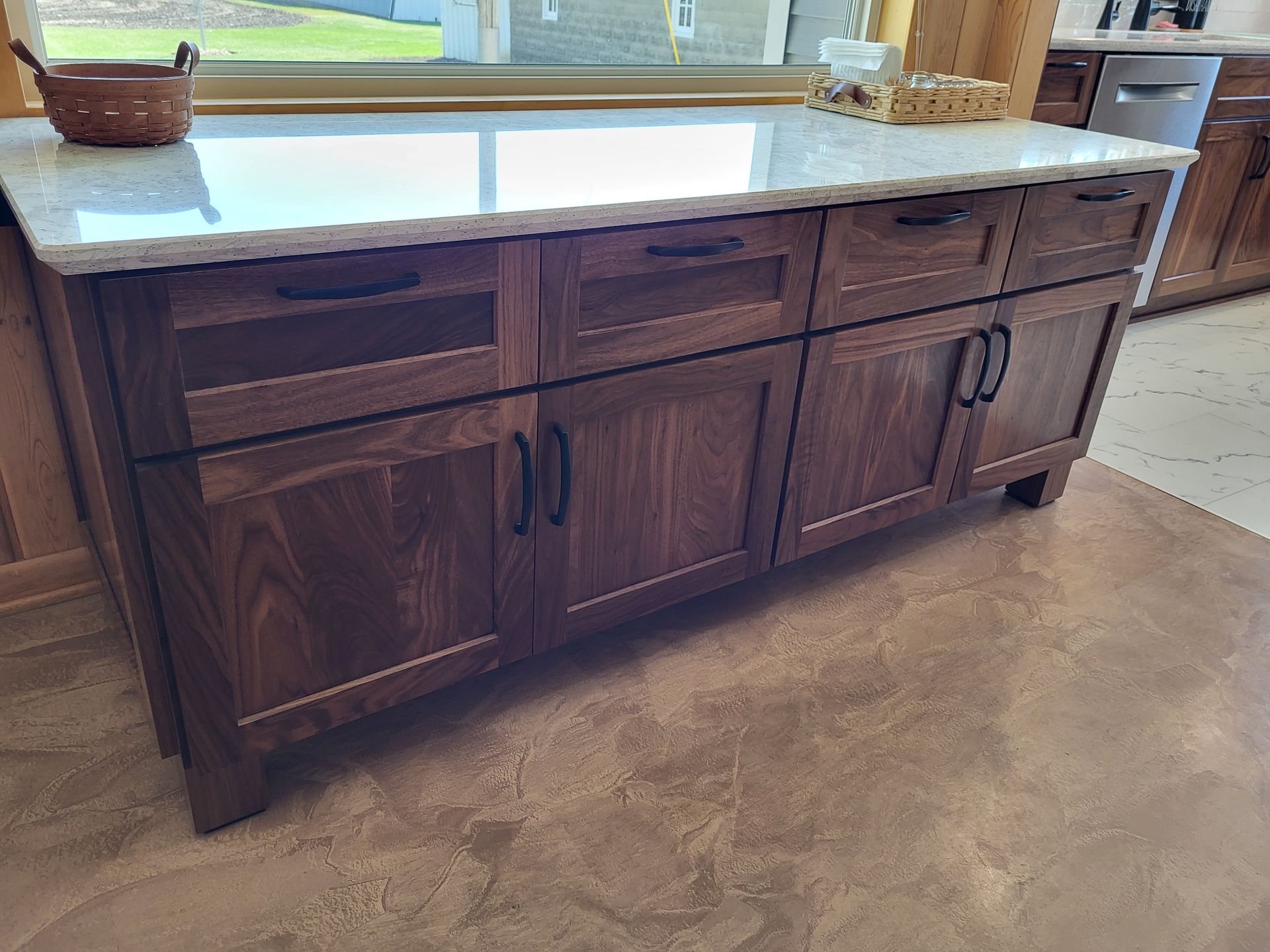 Dark wood kitchen island with white countertop, cabinets, drawers, and black hardware.