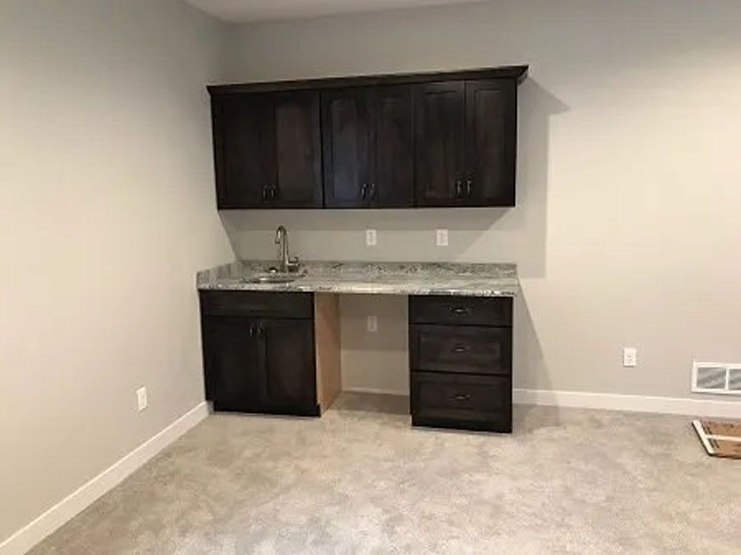 Dark cabinets, granite countertop, and sink in a small room.