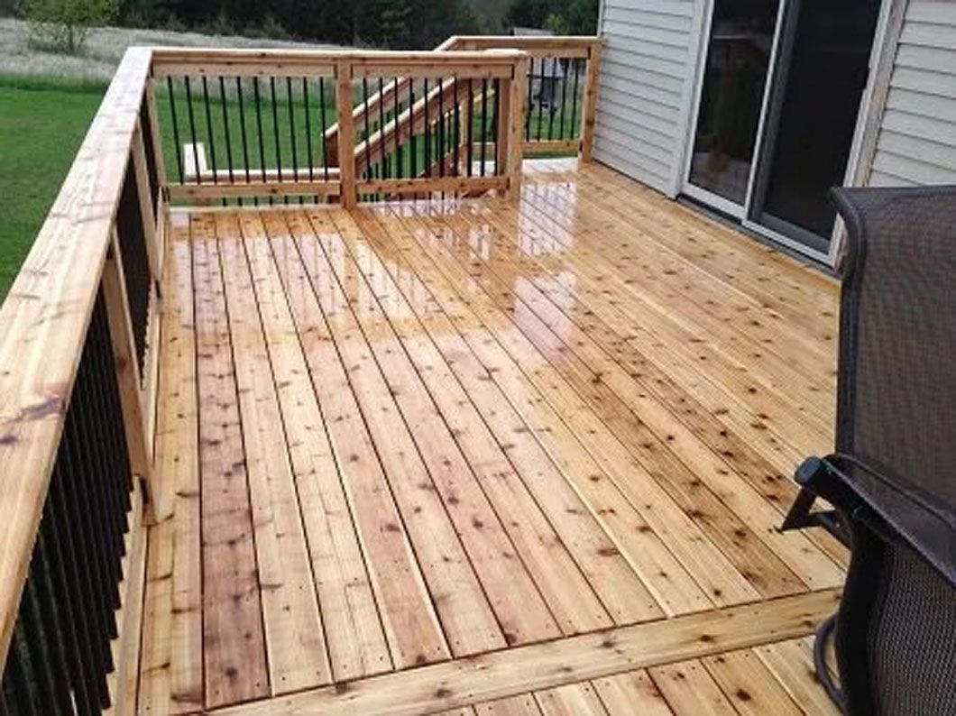 Wooden deck with wet boards, black railing, and access to a sliding glass door.