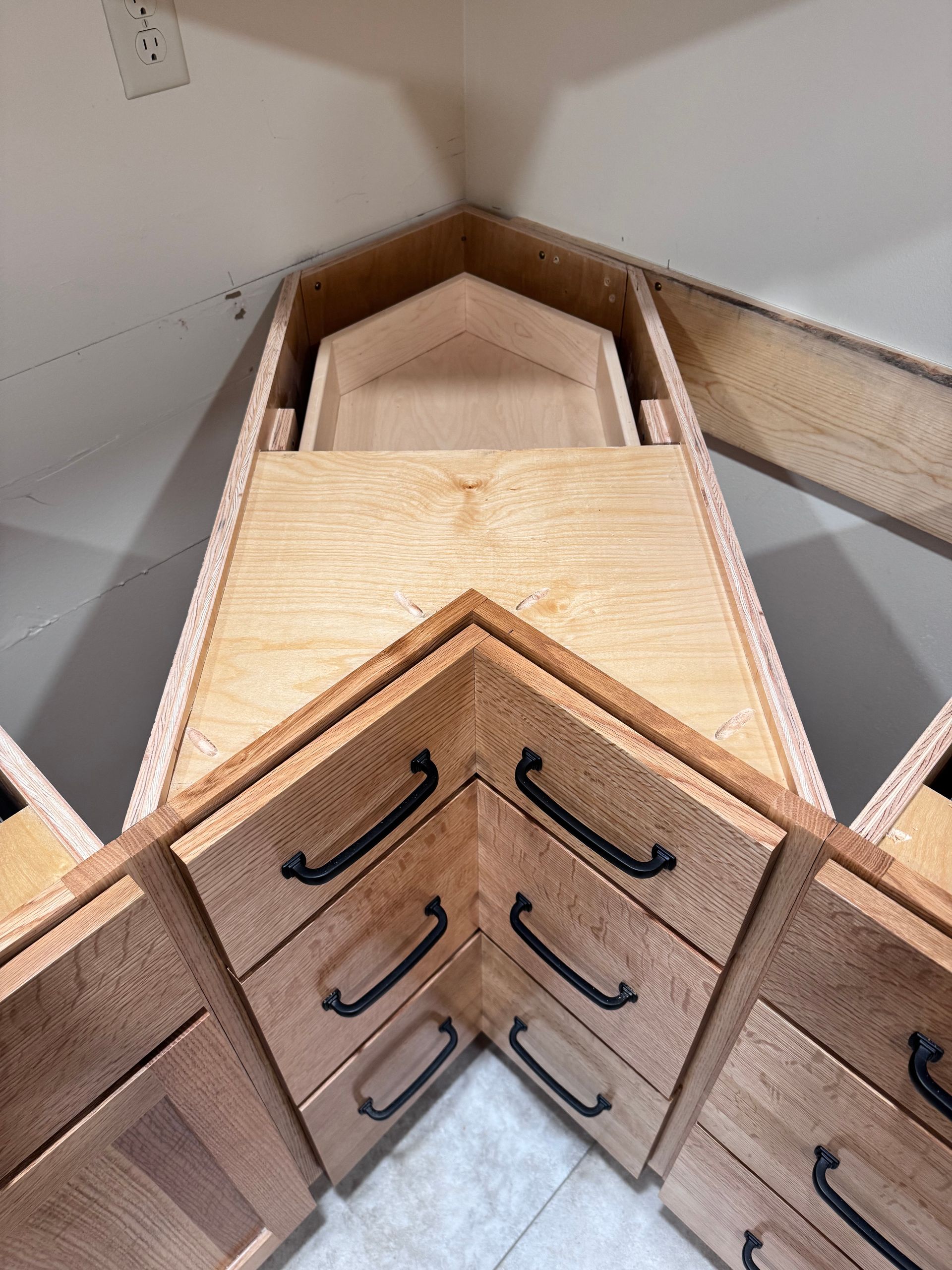 Corner kitchen cabinets with drawers and a hidden pull-out shelf, all made of wood.