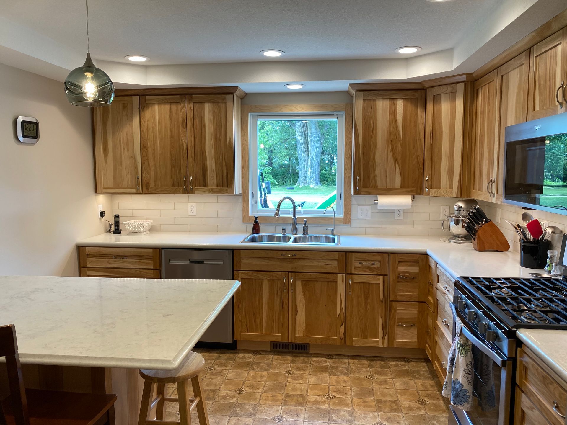 Kitchen with light wood cabinets, white countertops, stainless appliances, and a window.