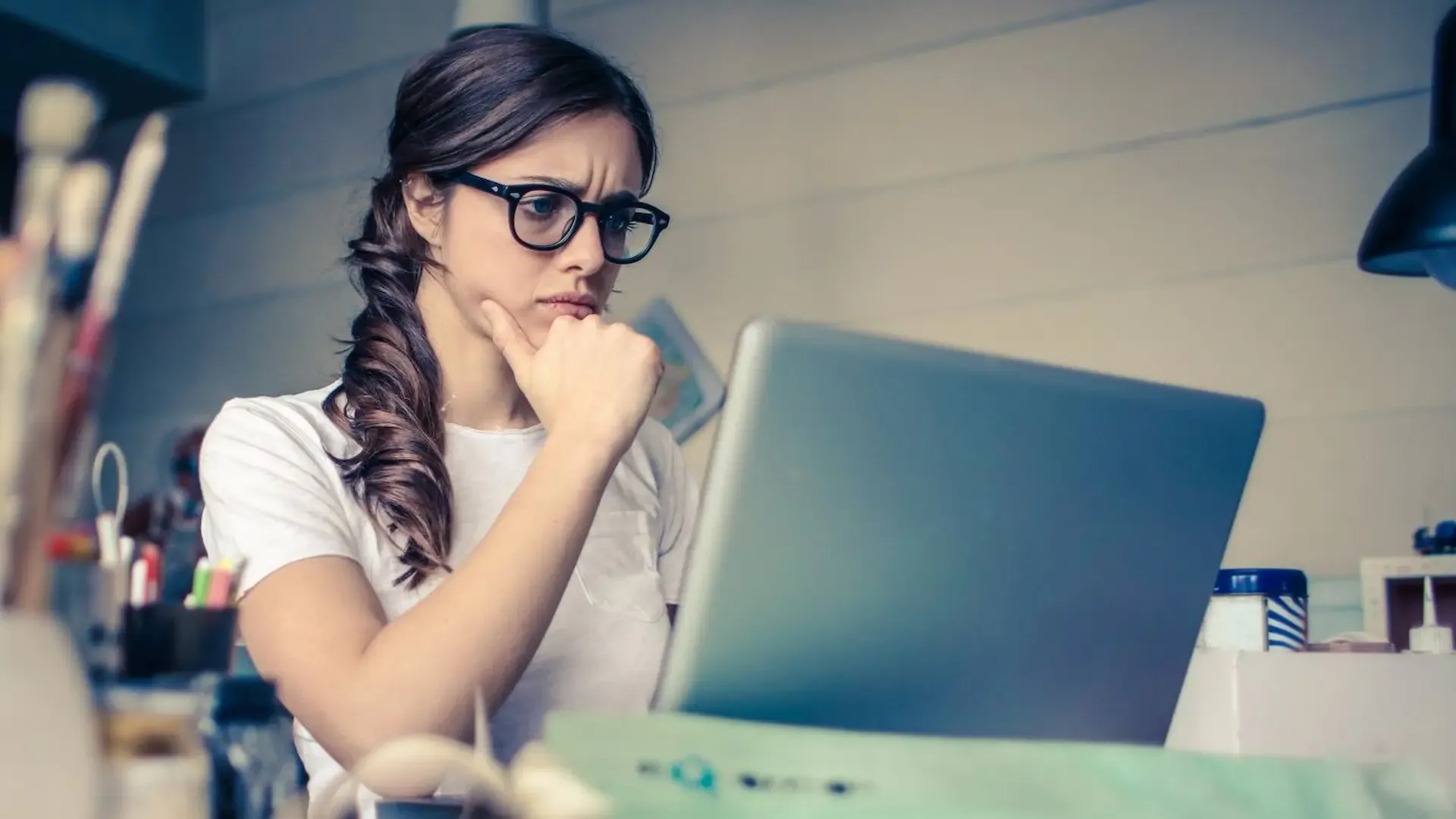 a woman thinking in front of a laptop