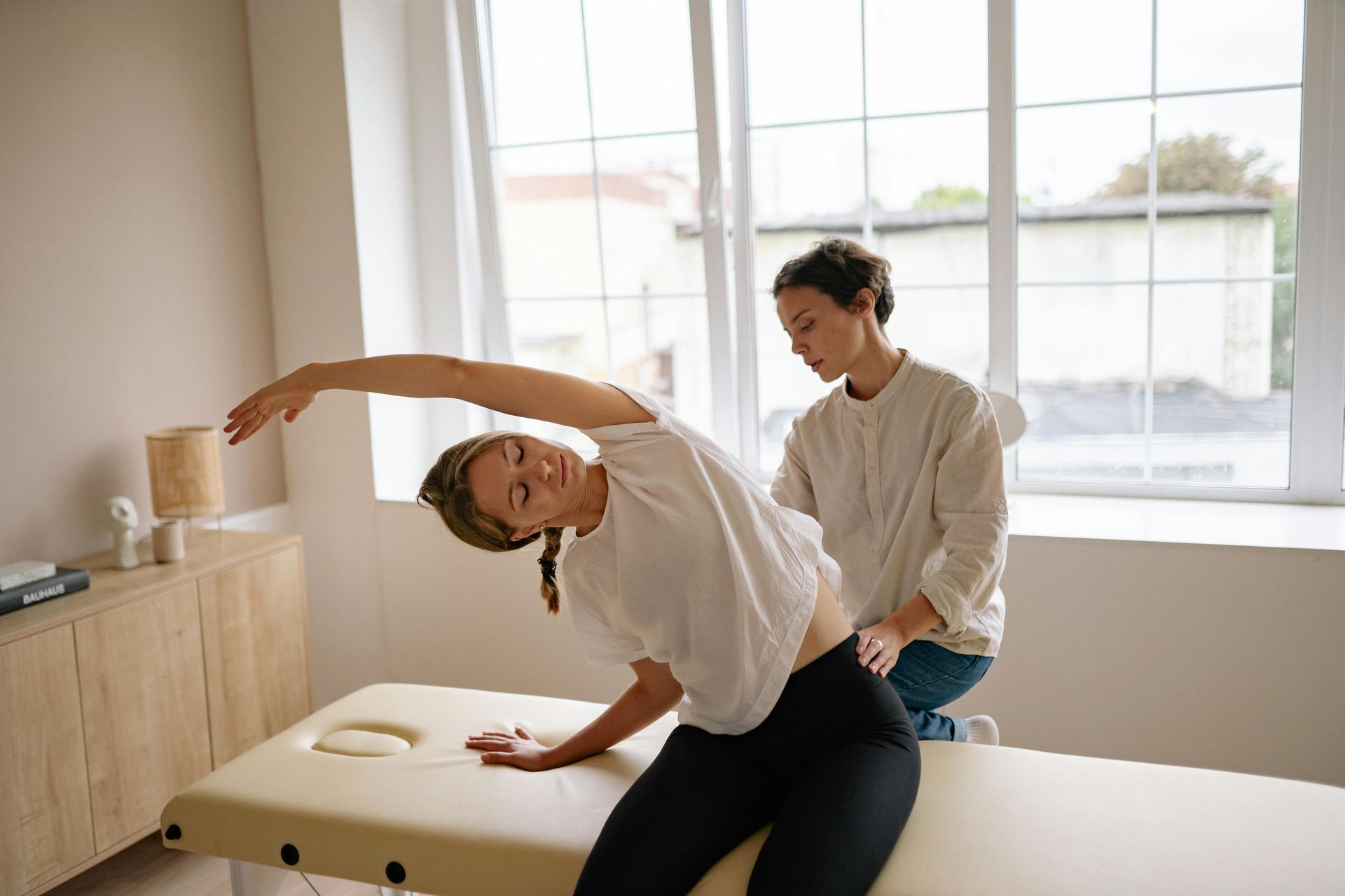 A woman is sitting on a table getting a massage from a doctor.