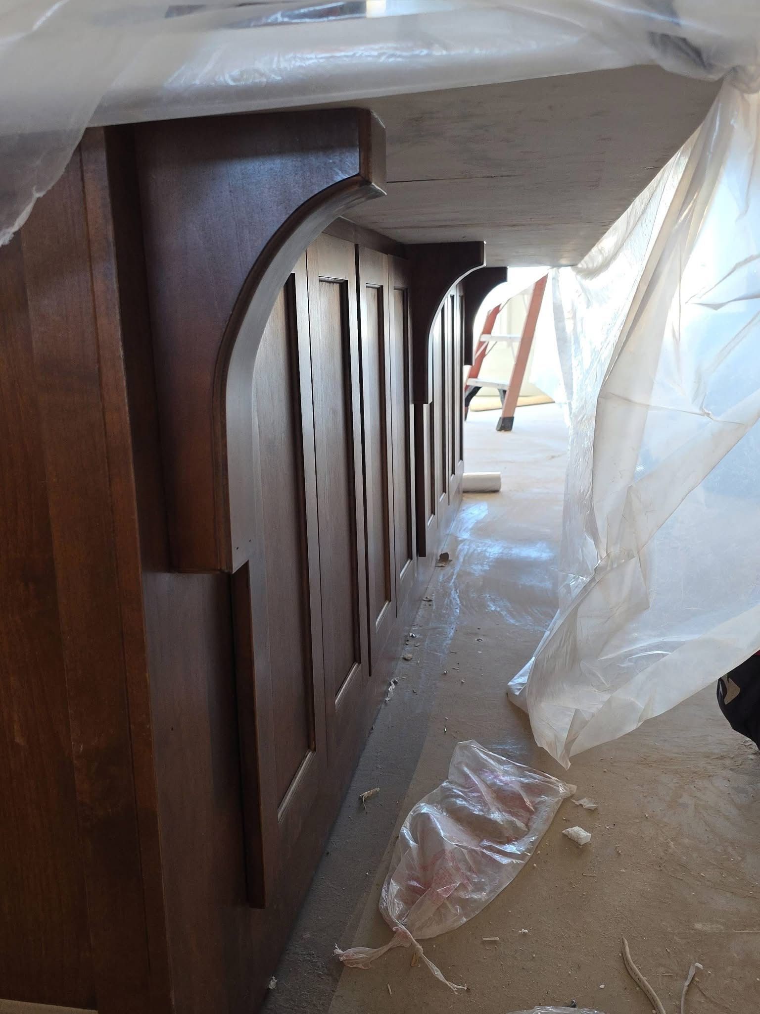 Wooden cabinet or panel pieces wrapped in plastic inside a construction area.