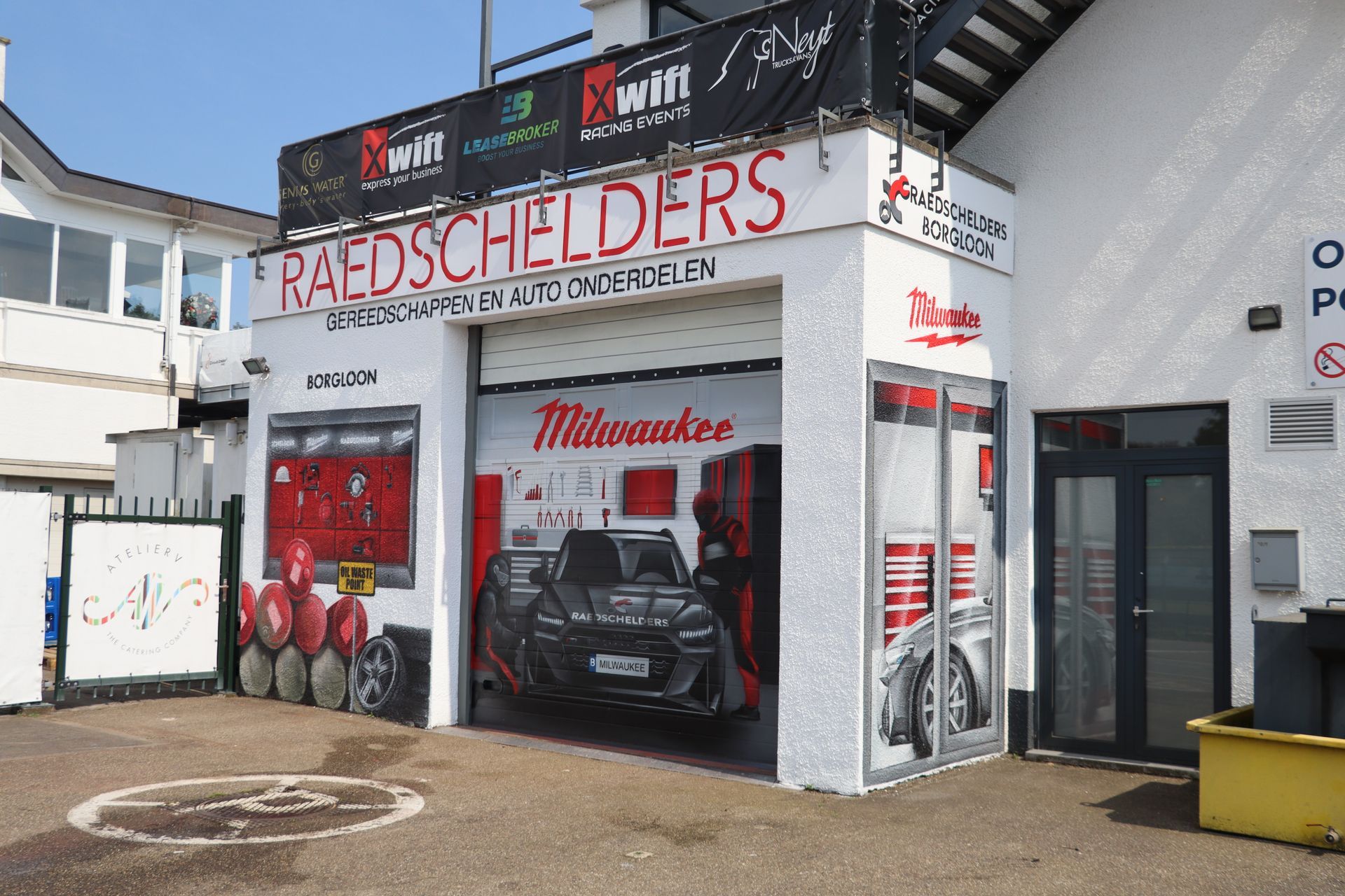 Overzicht van de volledige muurschildering op Circuit Zolder, met een Audi RS6, een realistisch raam en de branding van Milwaukee-tools.