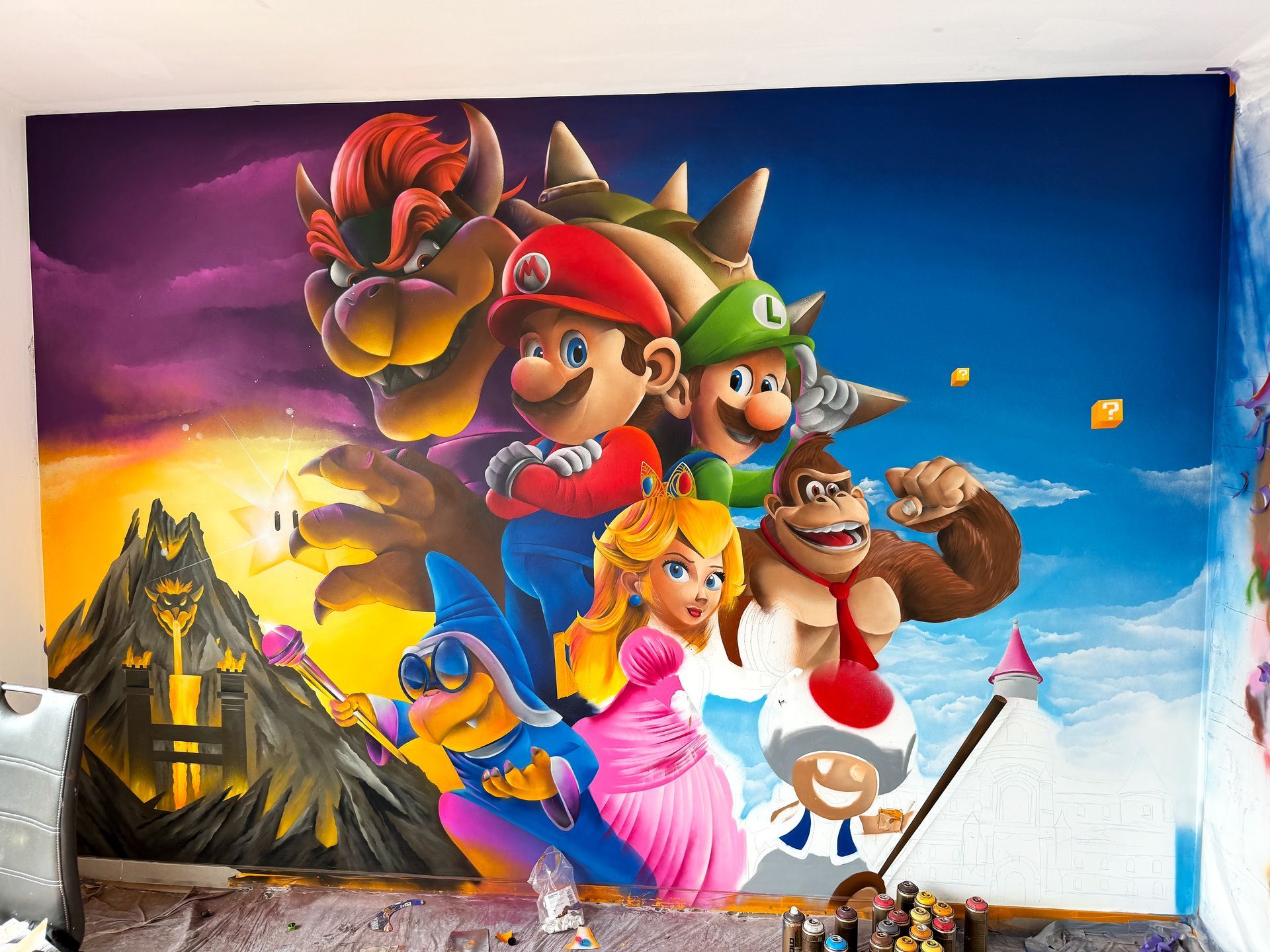 Werk in uitvoering: Mario Bros muurschildering in een kinderkamer, met spuitbussen en schetsdetails.